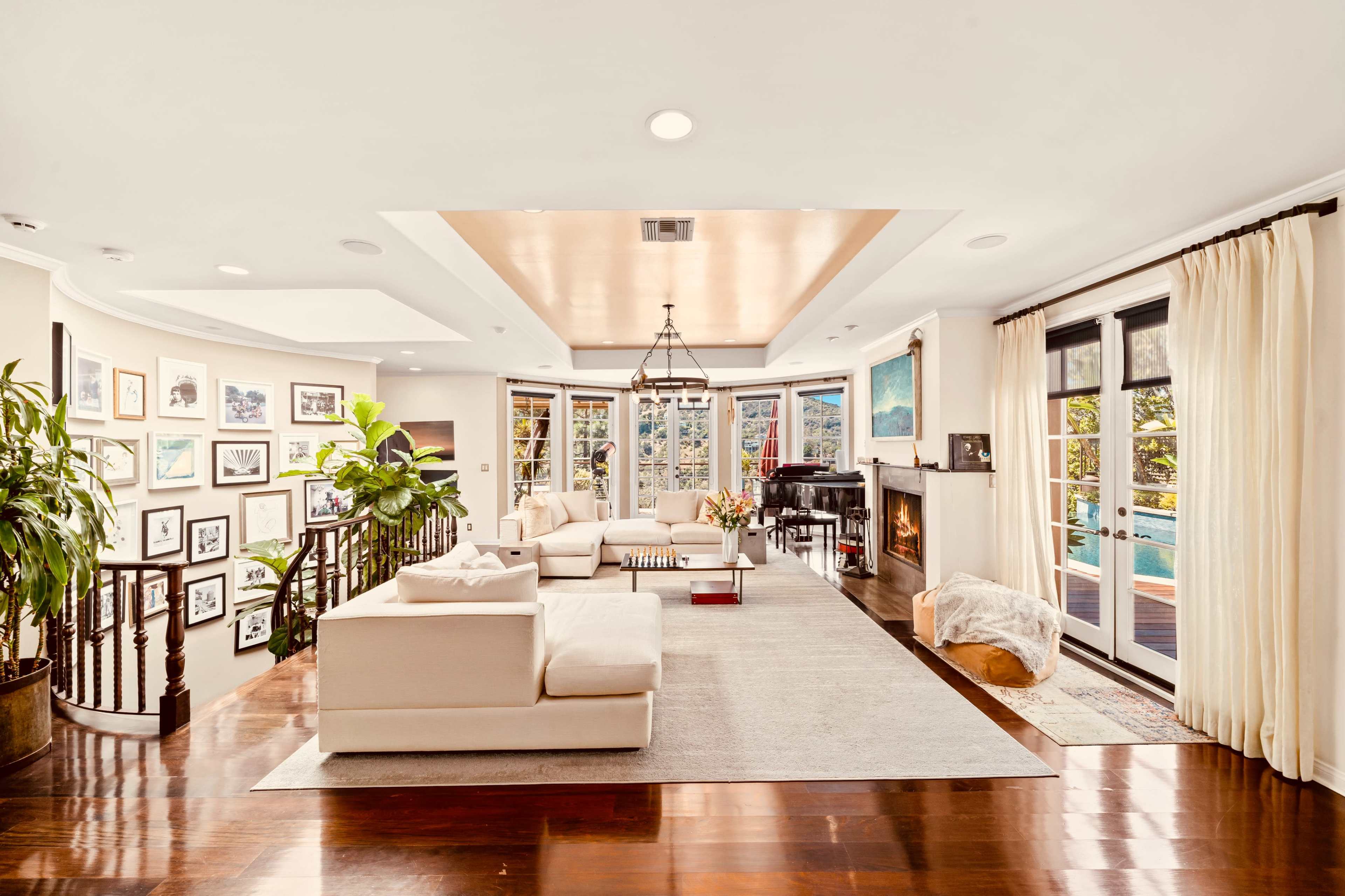 A spacious living room features a light-colored sectional sofa, a large area rug, and gallery walls filled with black-and-white photographs.