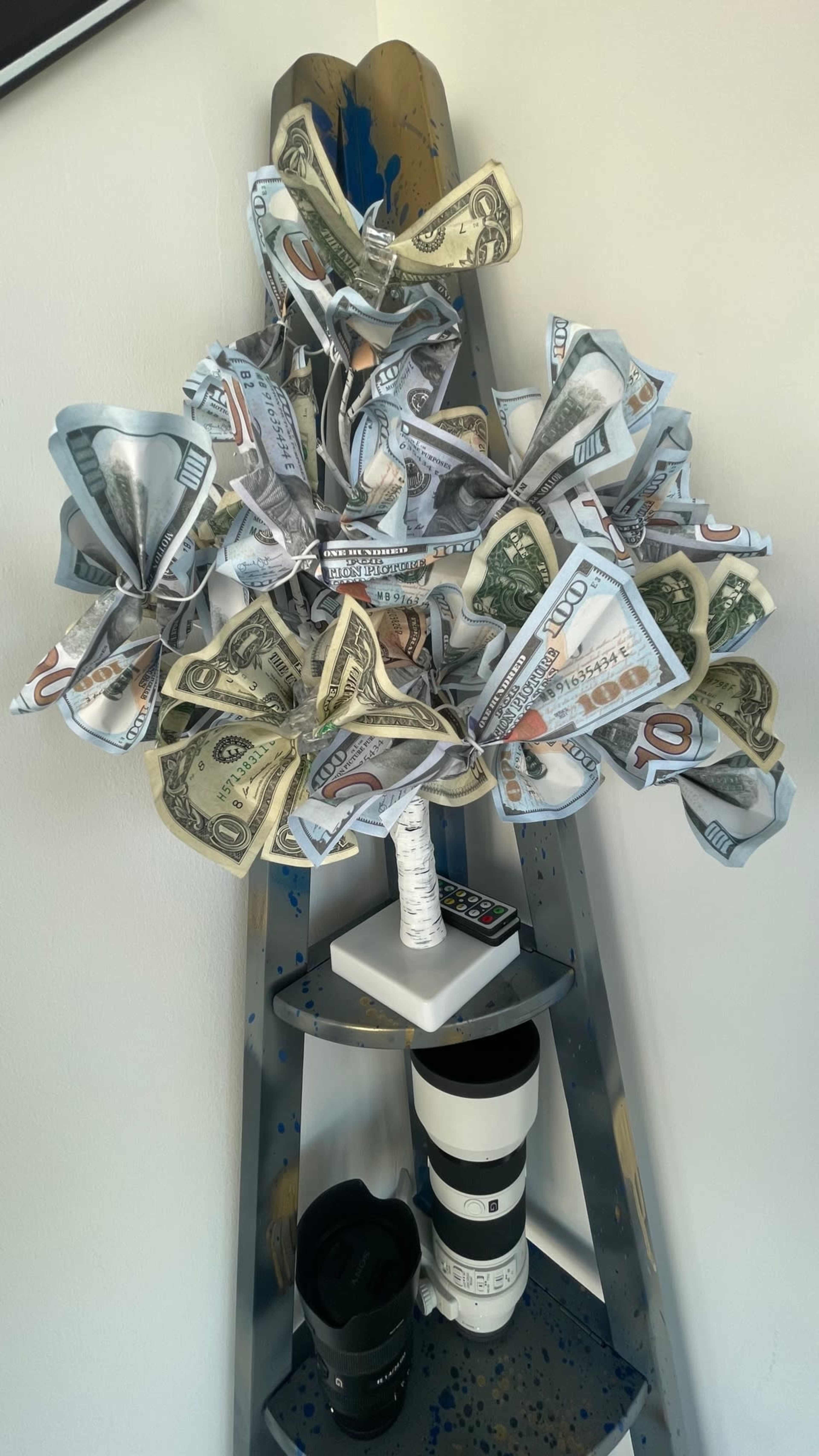 A decorative display features a ladder holding a stylized arrangement of money origami resembling flowers.