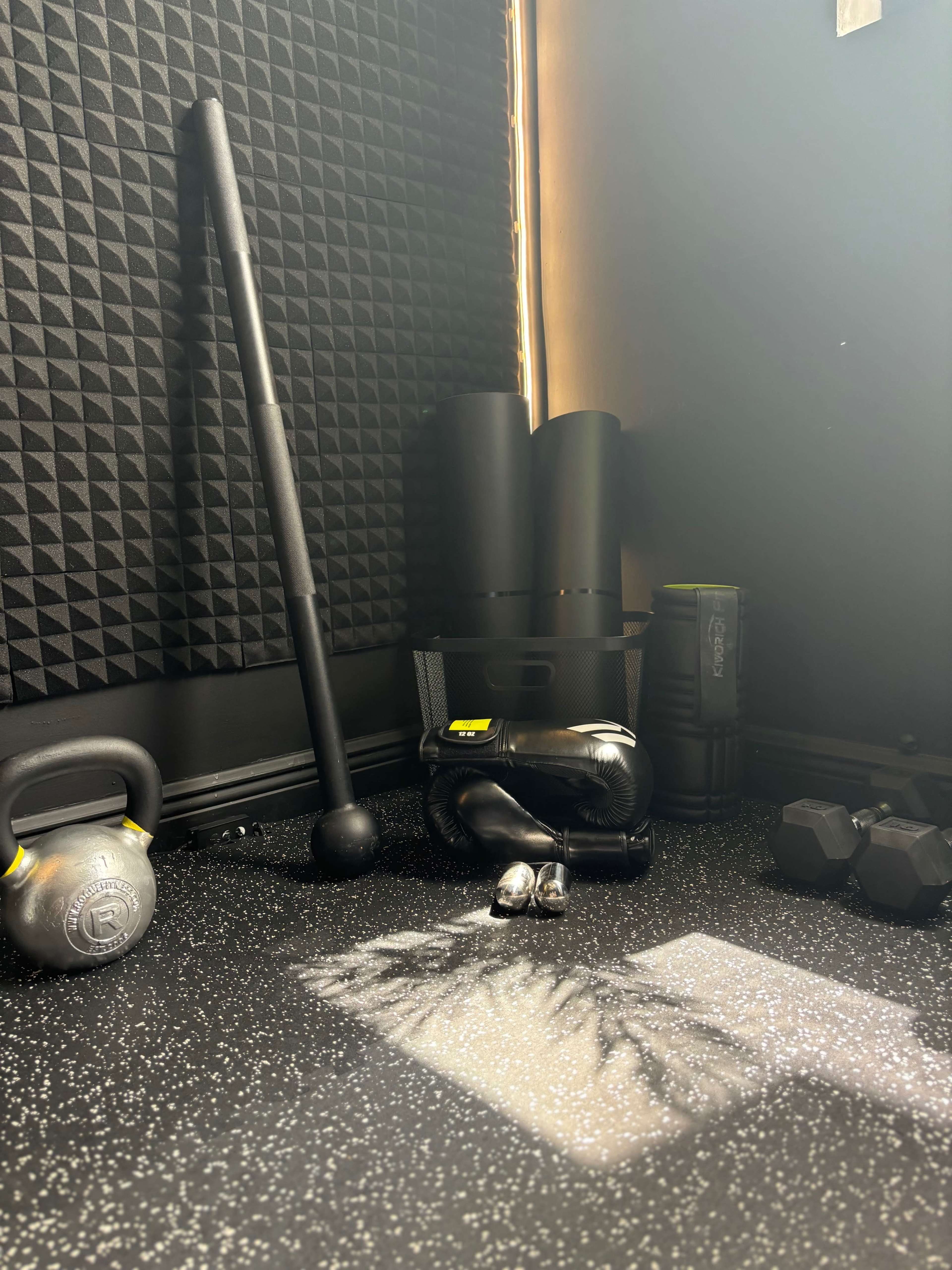A corner of a fitness area featuring various workout equipment, including weights, a kettlebell, and a pair of boxing gloves.