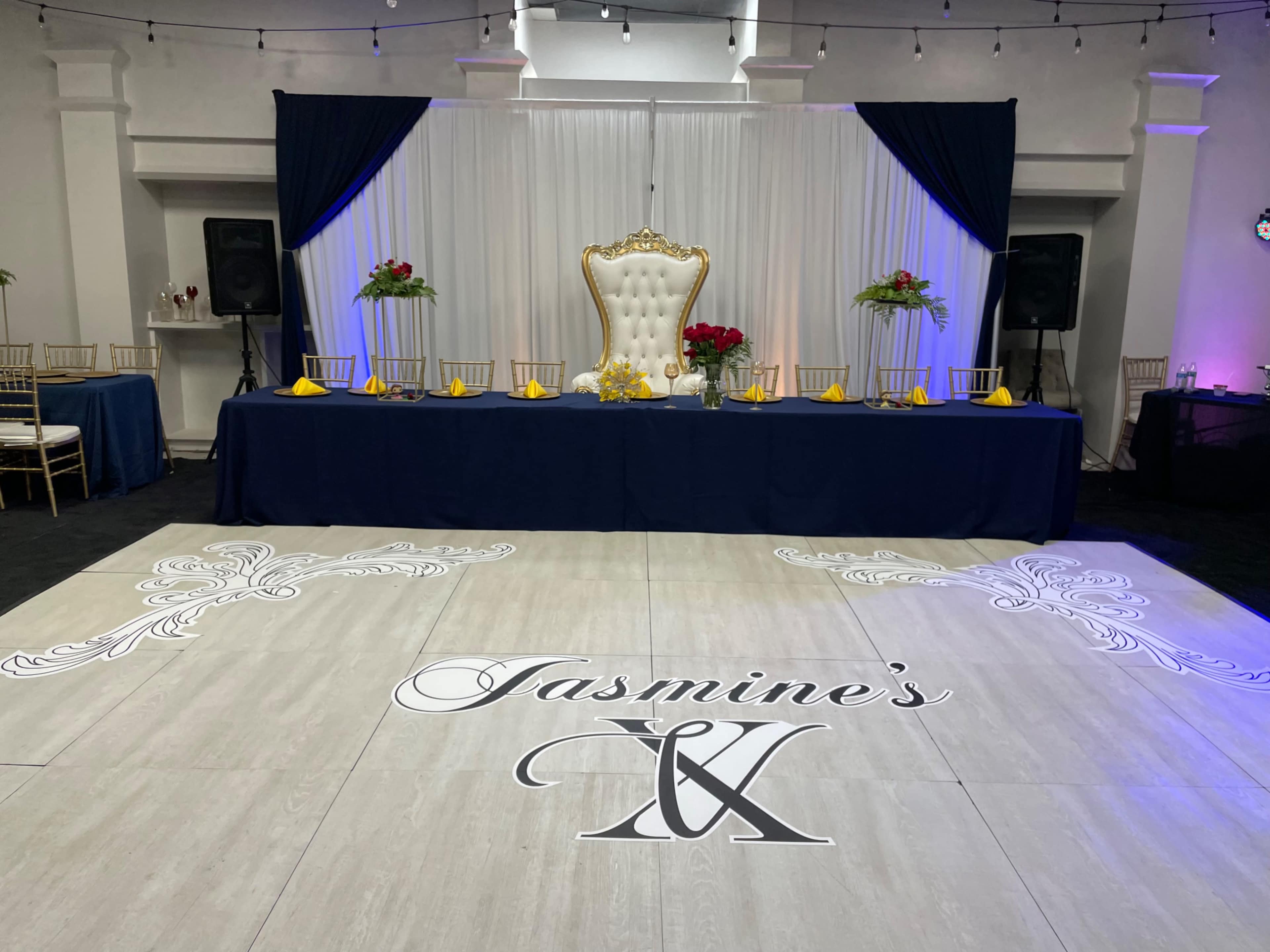 A elegantly decorated banquet scene featuring a large golden throne, a table set with yellow napkins, and a dance floor displaying the name "Jasmine's."