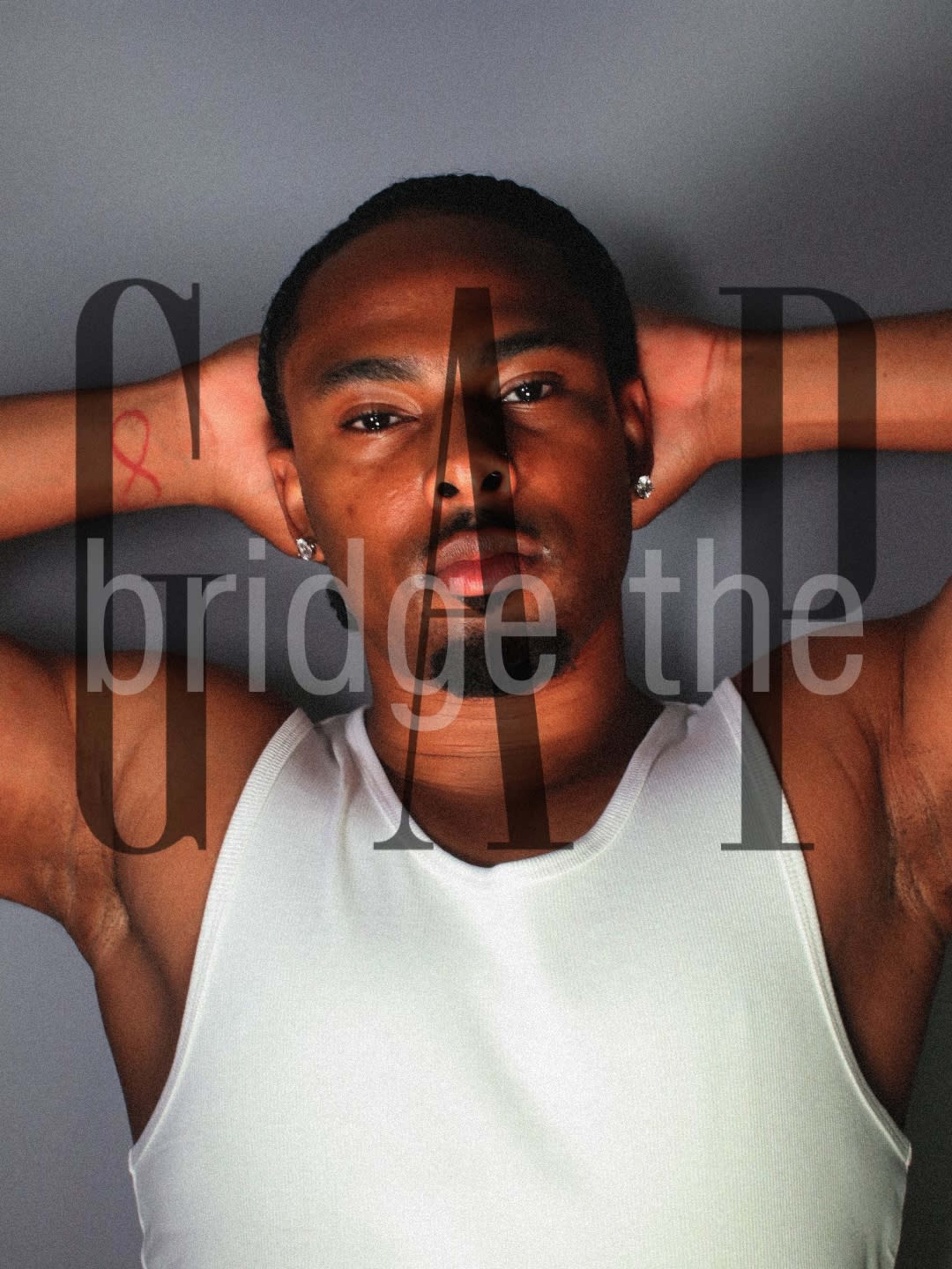 A man is posing with his hands behind his head while wearing a white tank top, and the words "bridge the GAP" are overlayed on the image.