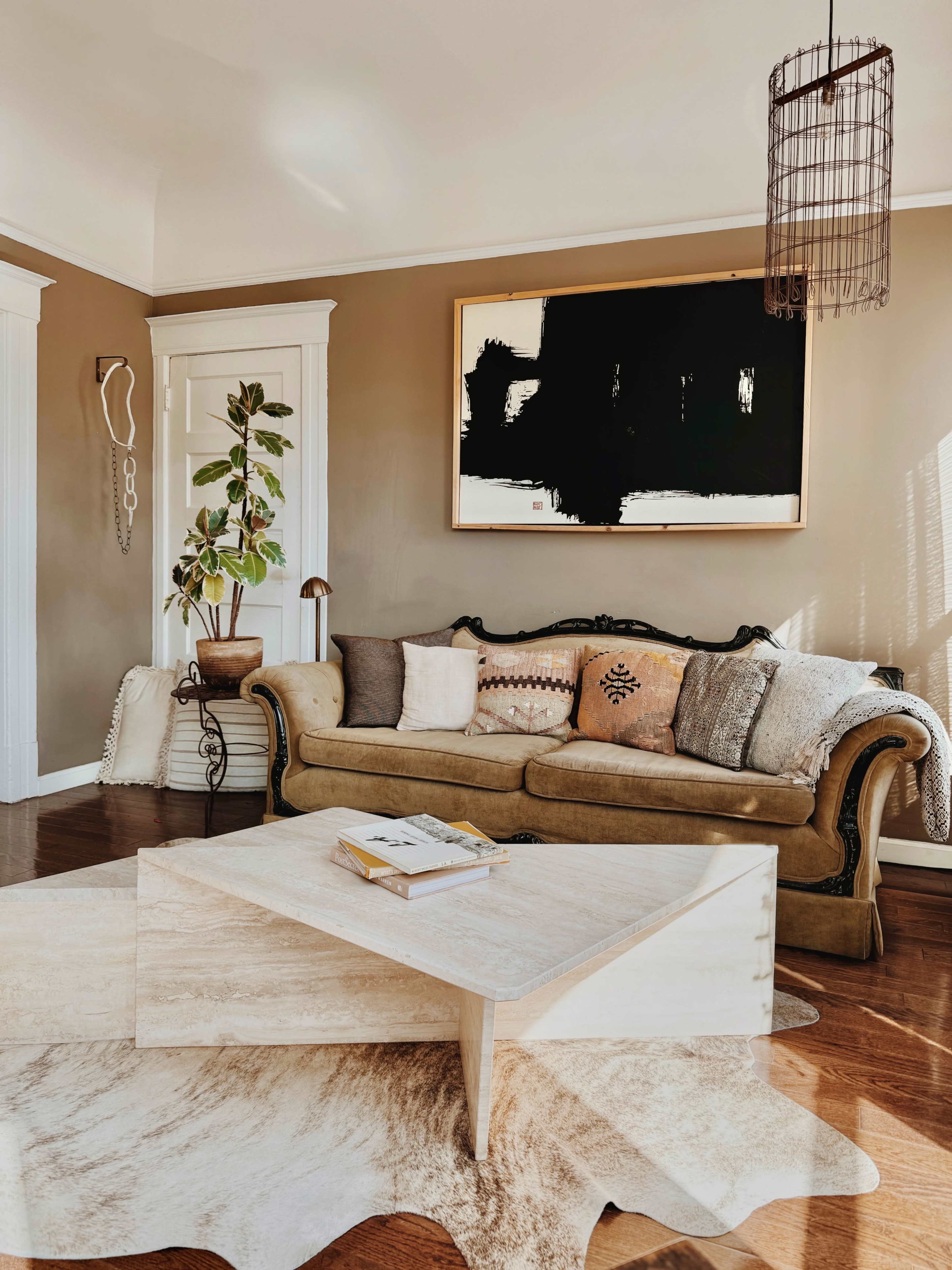 The image shows a cozy living room with a vintage sofa, a coffee table, and a large abstract painting on the wall.