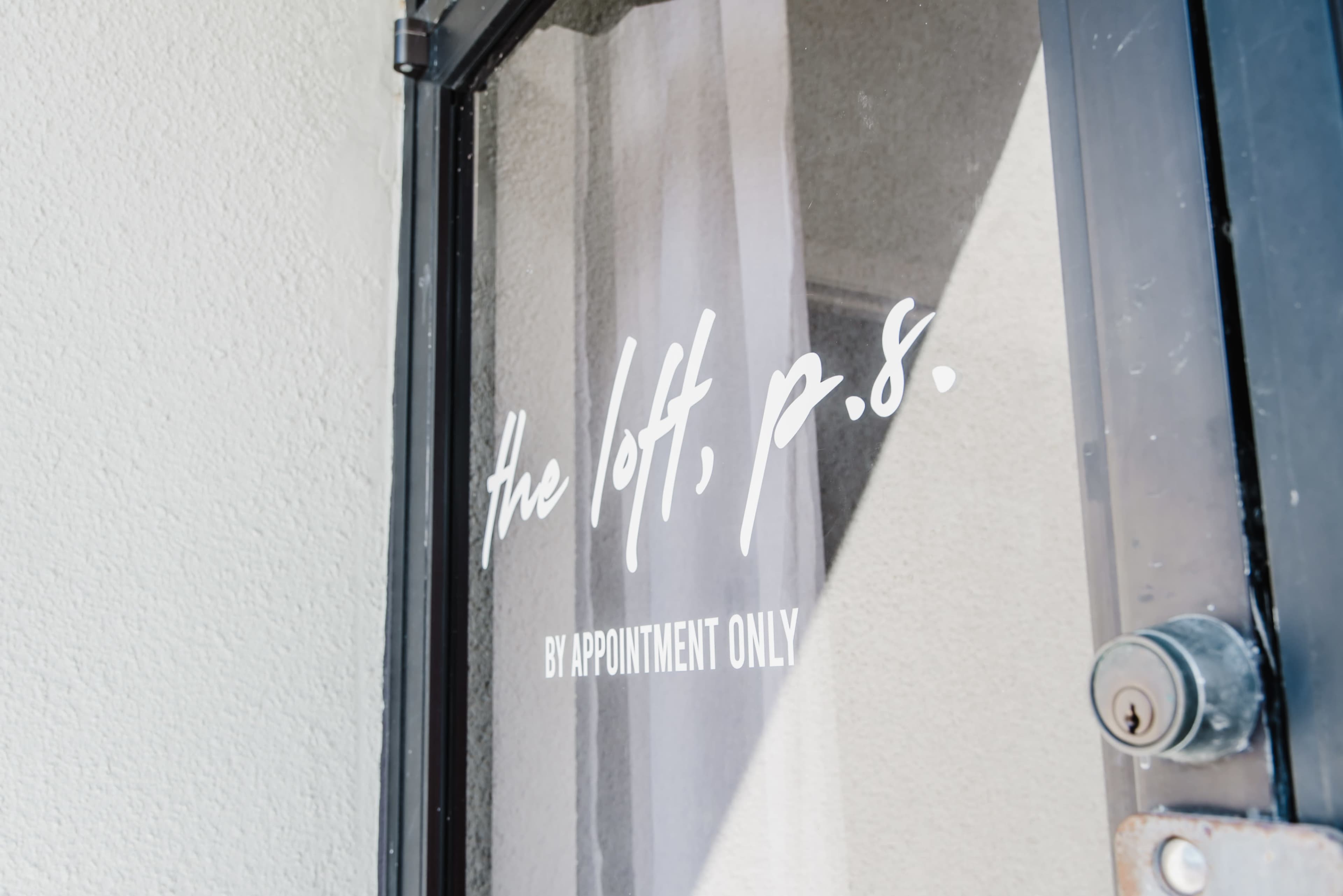 A glass door features the text "the loft, p.s." and "BY APPOINTMENT ONLY" on a white background.