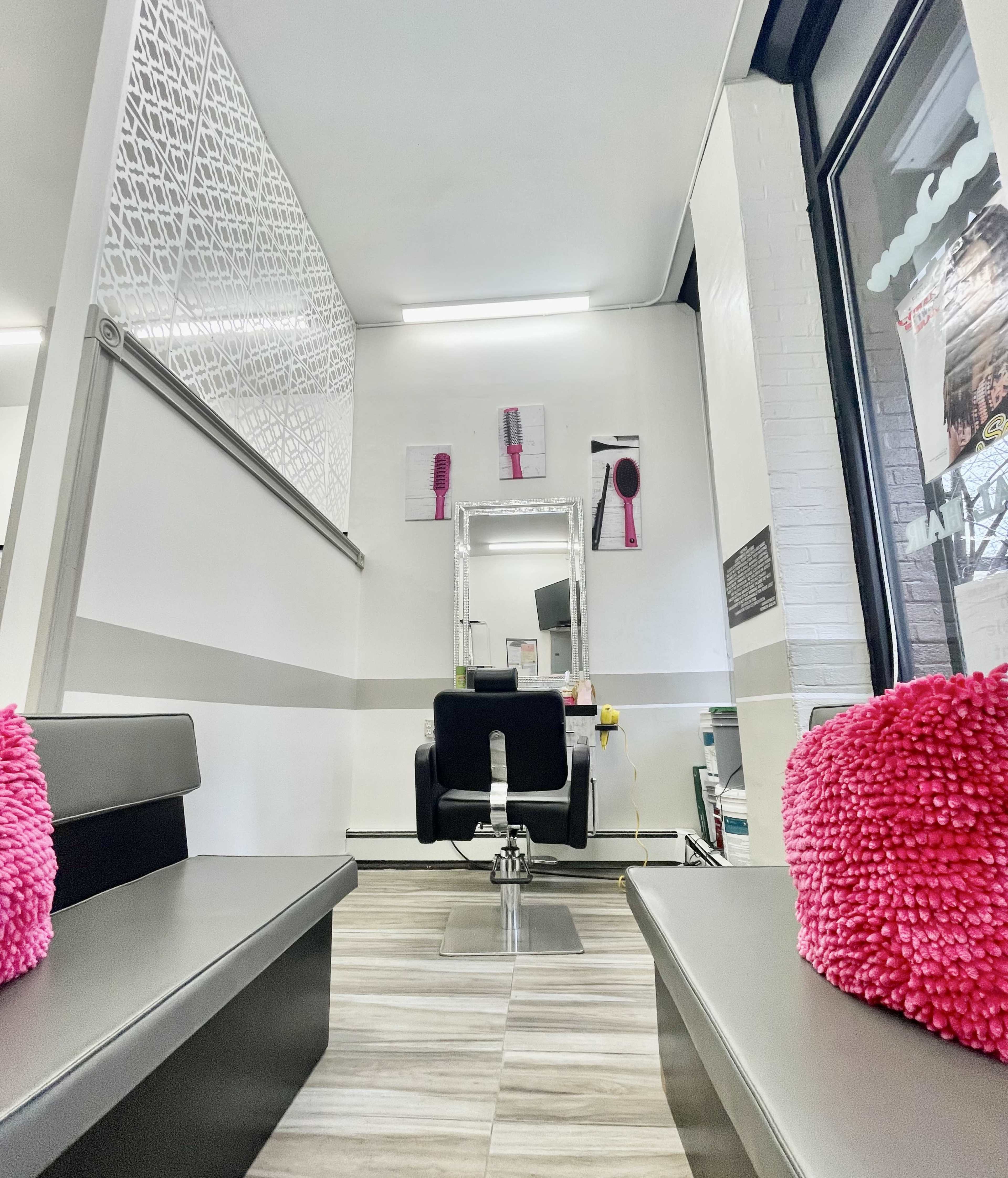 The image shows a hair salon interior with a mirrored styling station and cushioned benches on either side, featuring pink decorative pillows.
