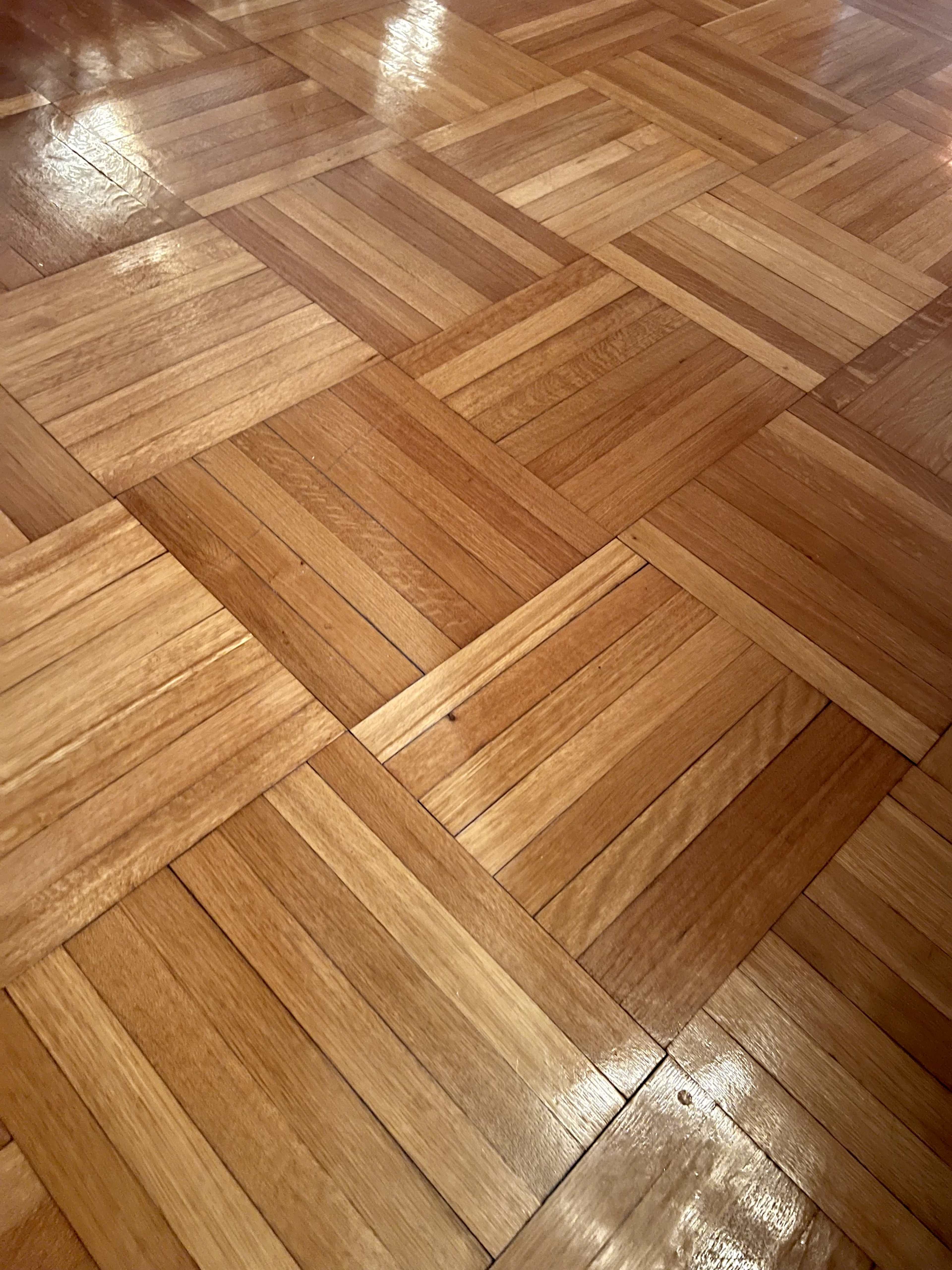 A section of wooden parquet flooring arranged in a geometric pattern.