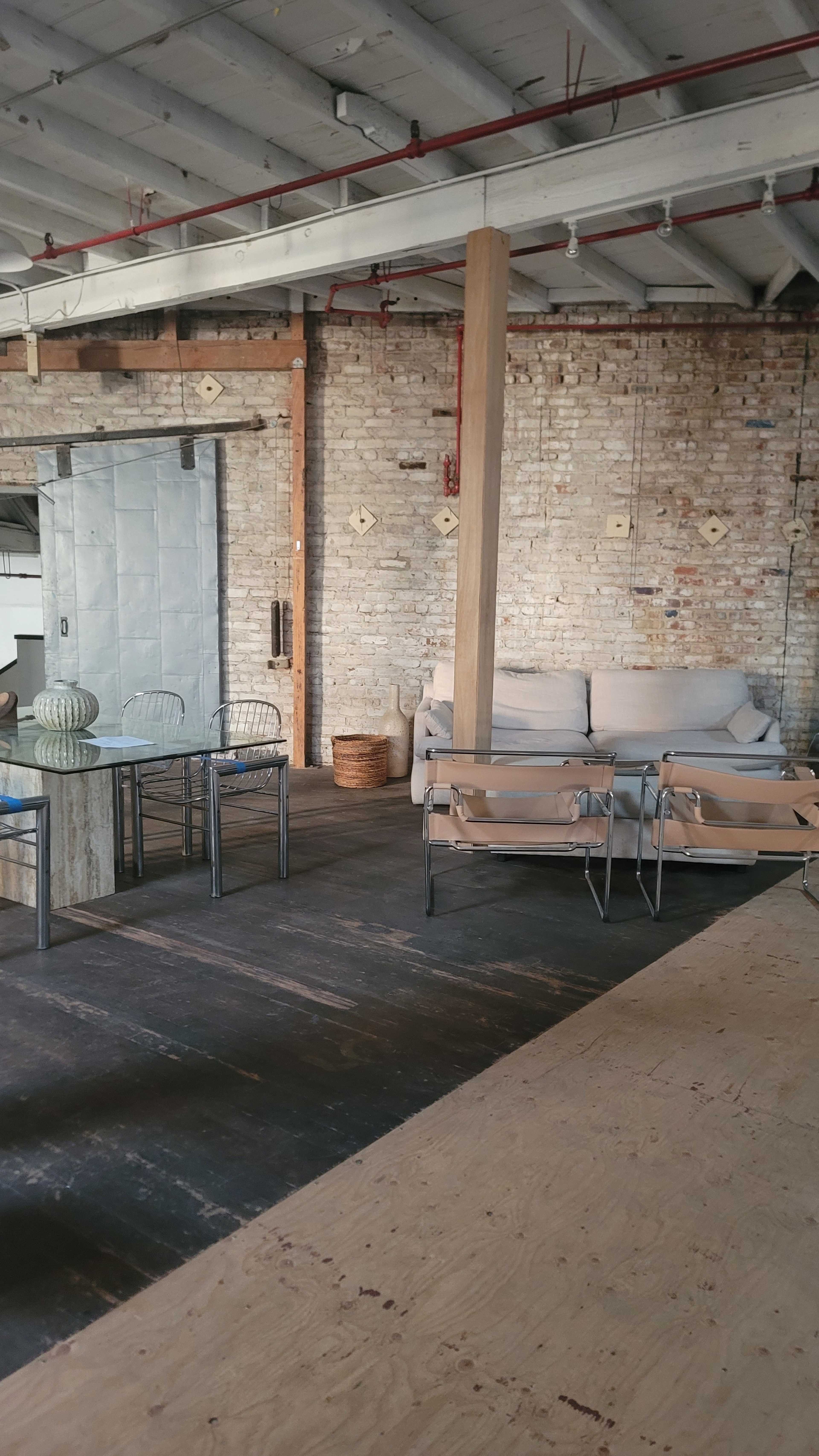A spacious interior featuring a sofa, a table with chairs, and exposed brick walls.