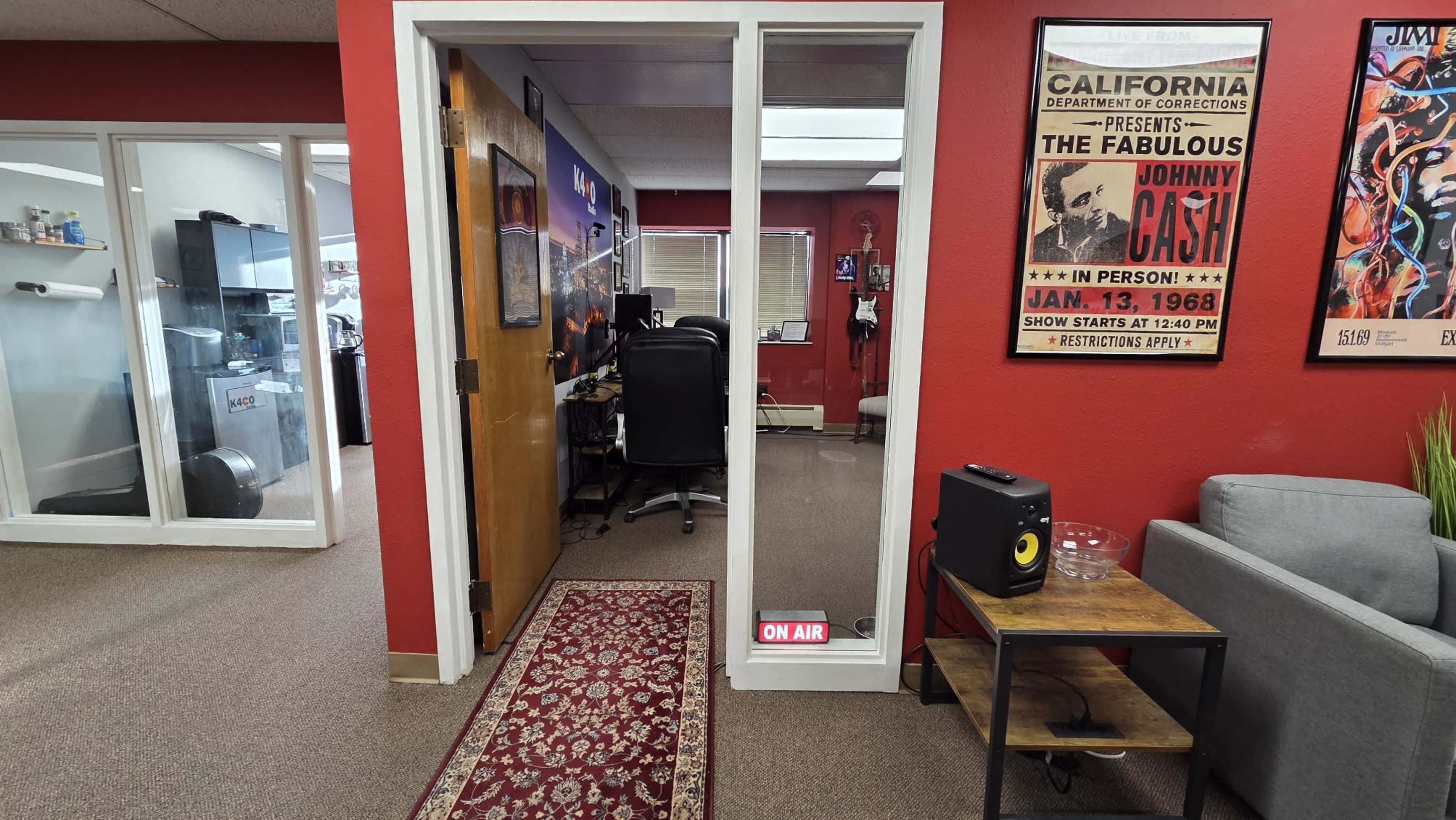 The image shows an office space with a visible doorway labeled "ON AIR," leading into a room featuring a desk and a chair.
