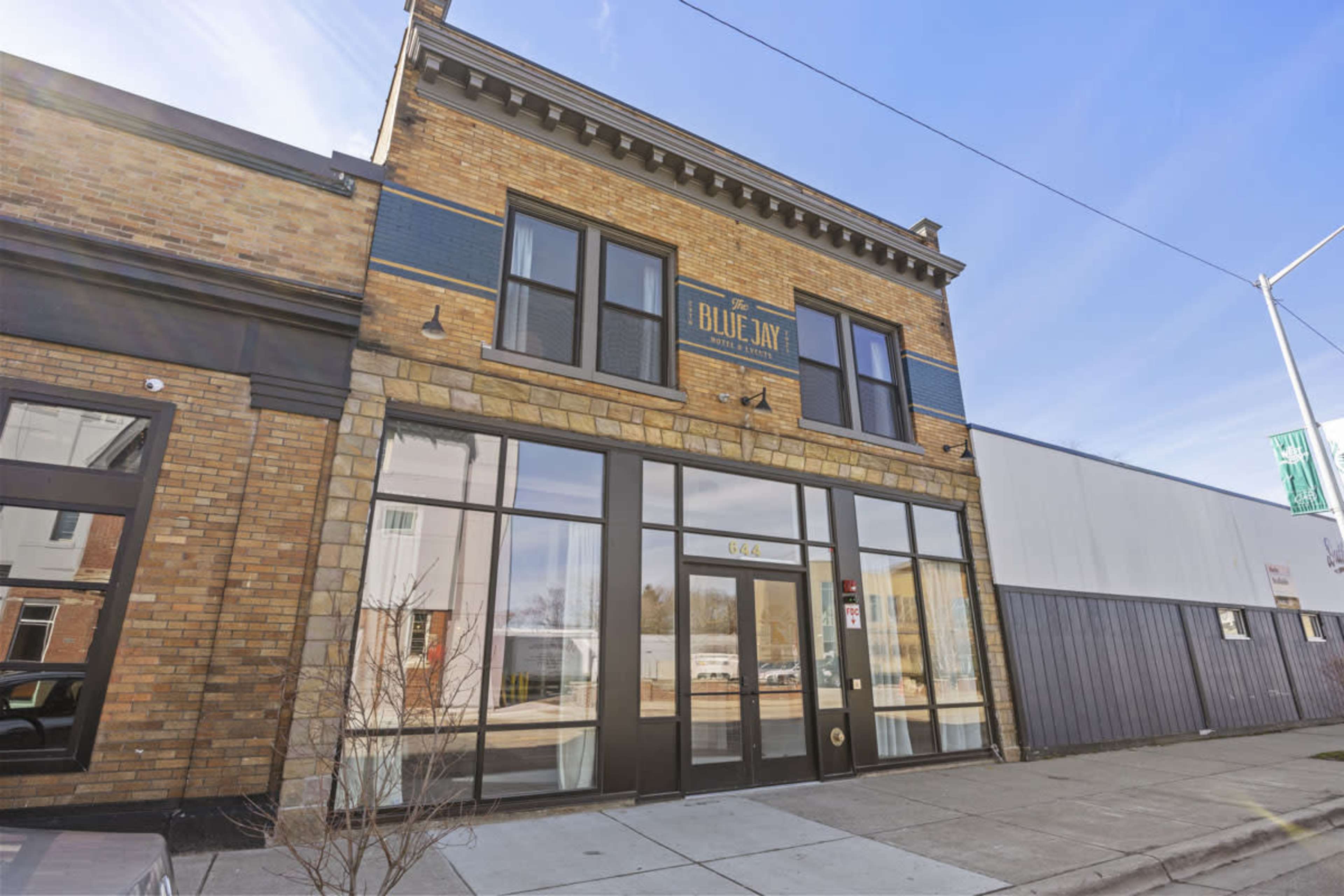 A two-story brick building with large glass windows, labeled "Blue Jay," located on a city street.