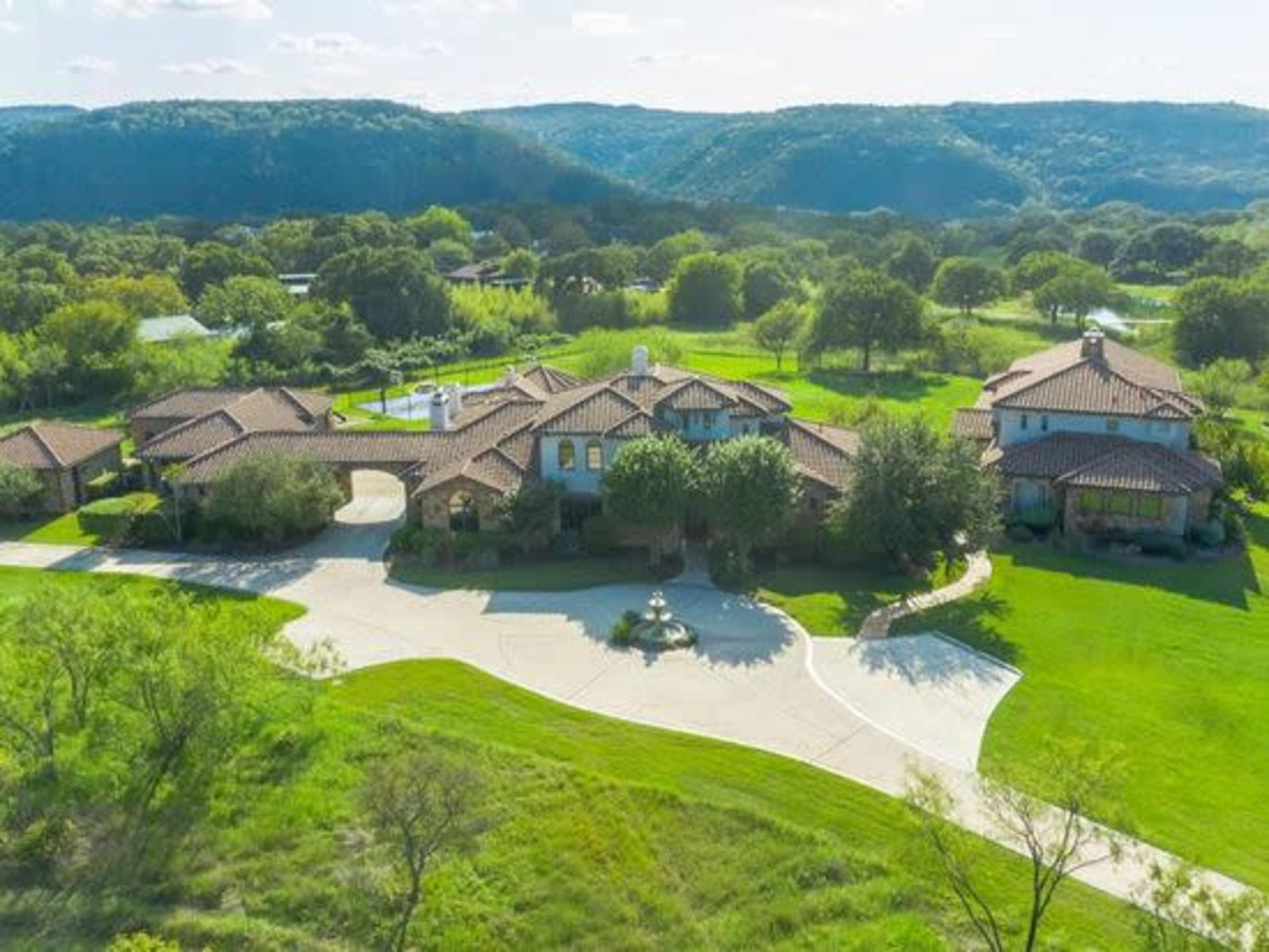 A large, sprawling estate with multiple structures surrounded by greenery and hills in the background.