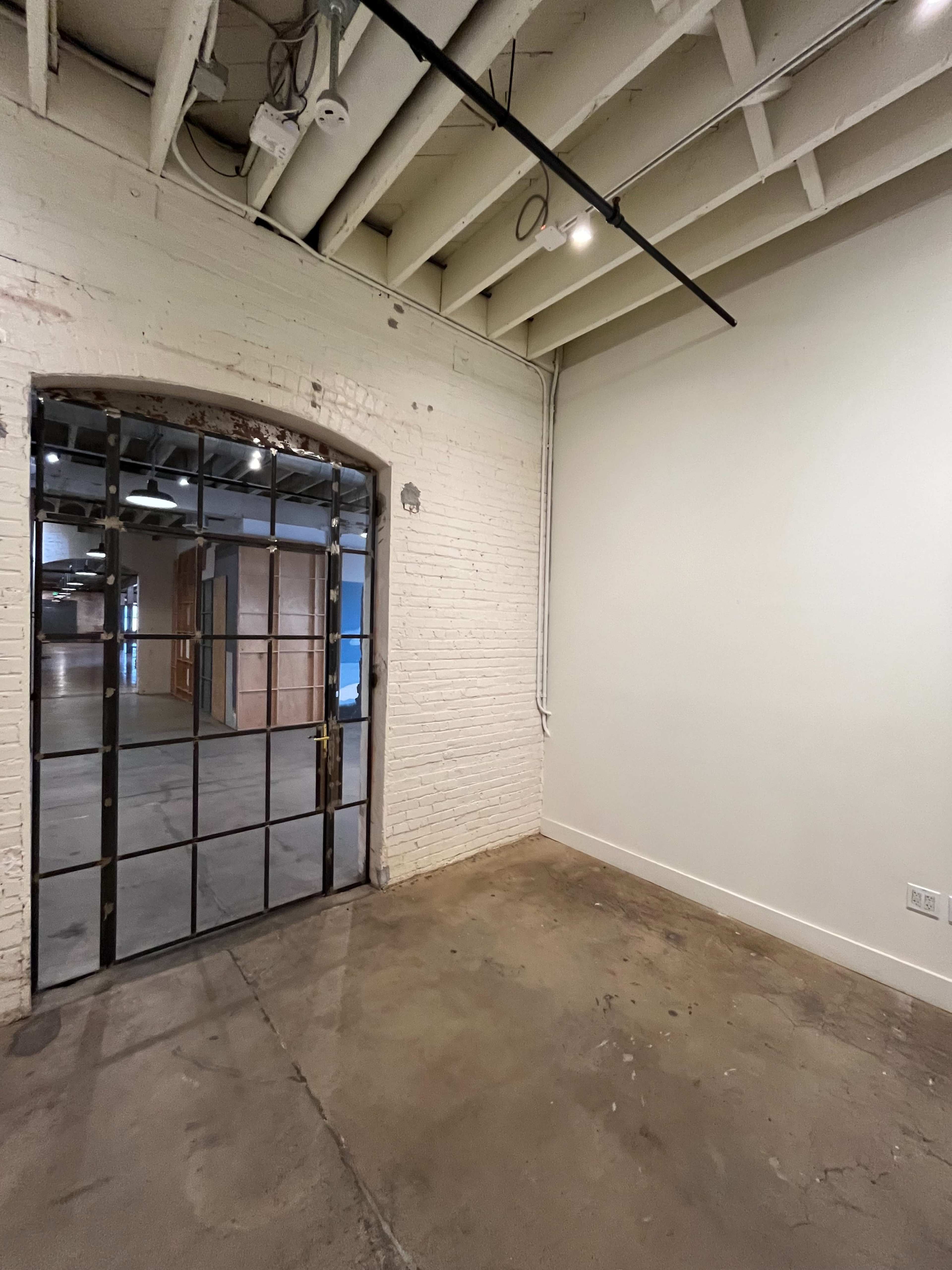 A spacious, industrial-style room with a large glass-paneled door leading to another area.