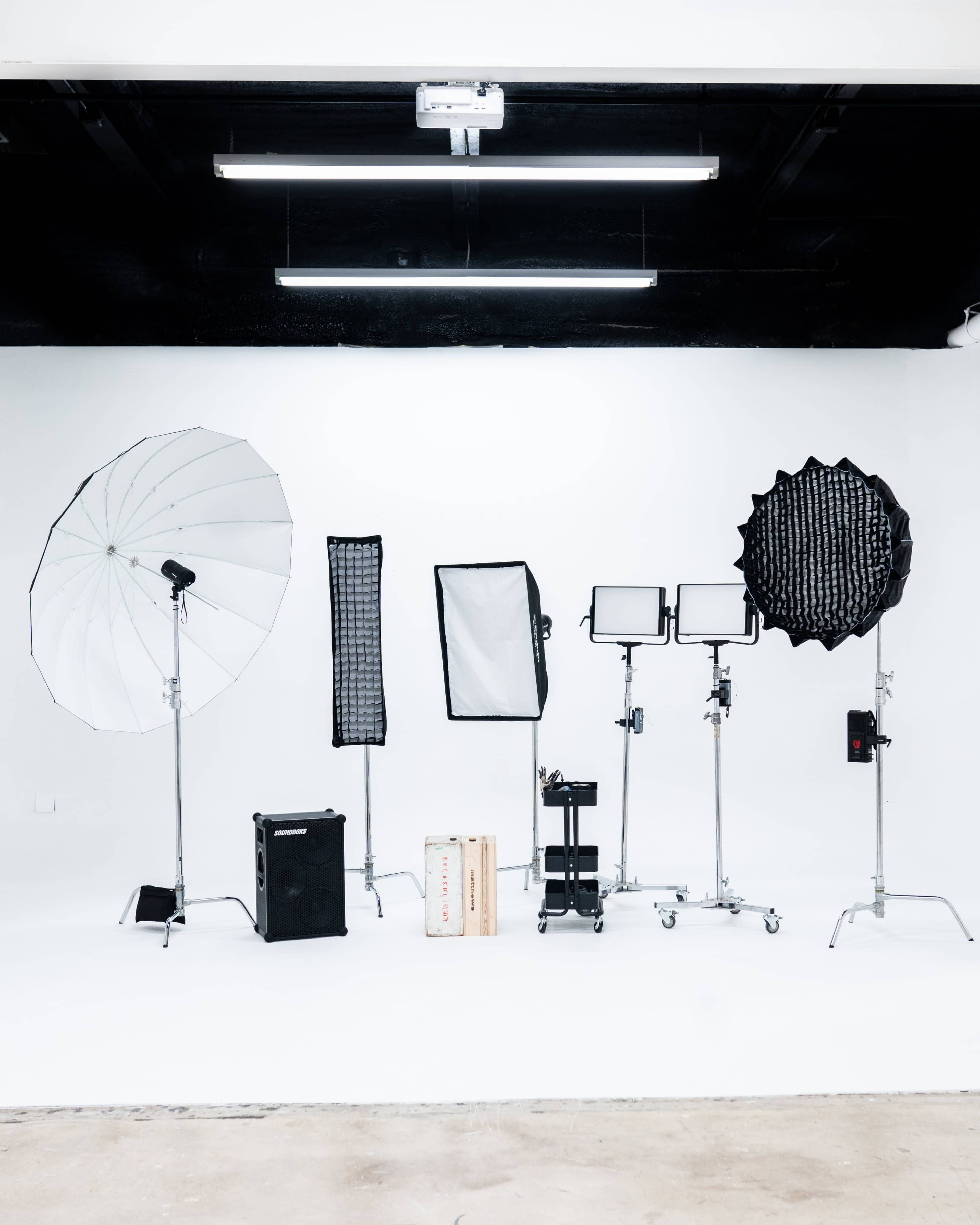 A photography studio setup with various lighting equipment arranged on a white backdrop.