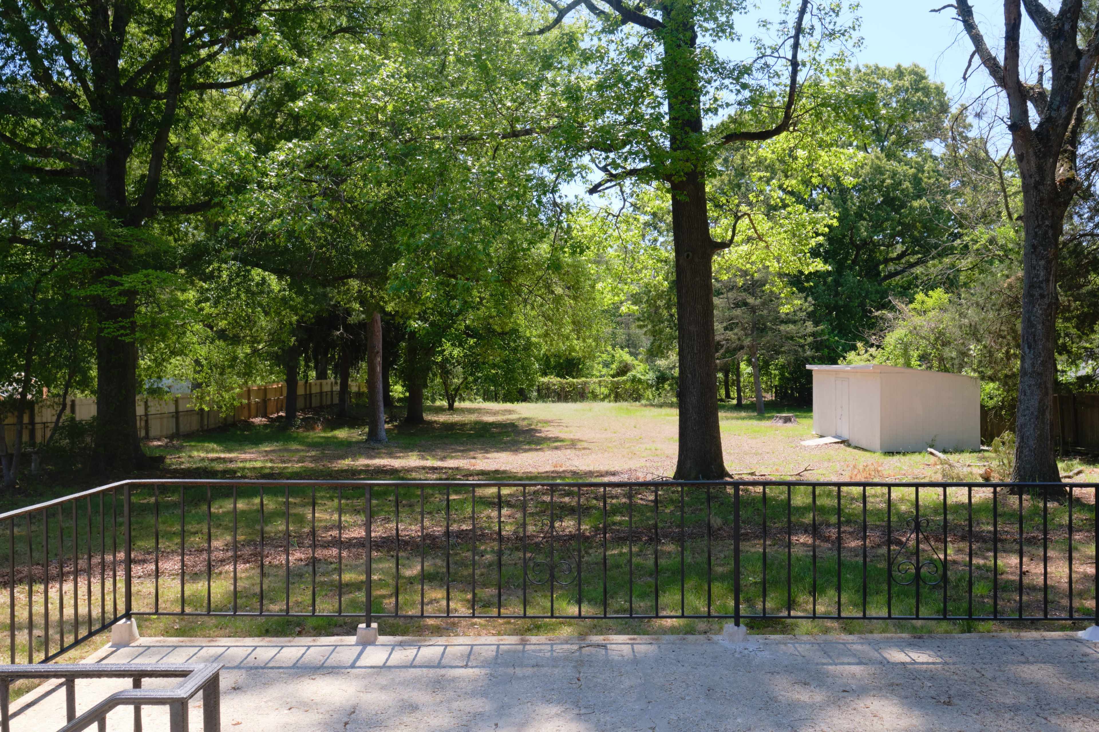 The image shows an open green field surrounded by trees, with a small shed visible on the right side.