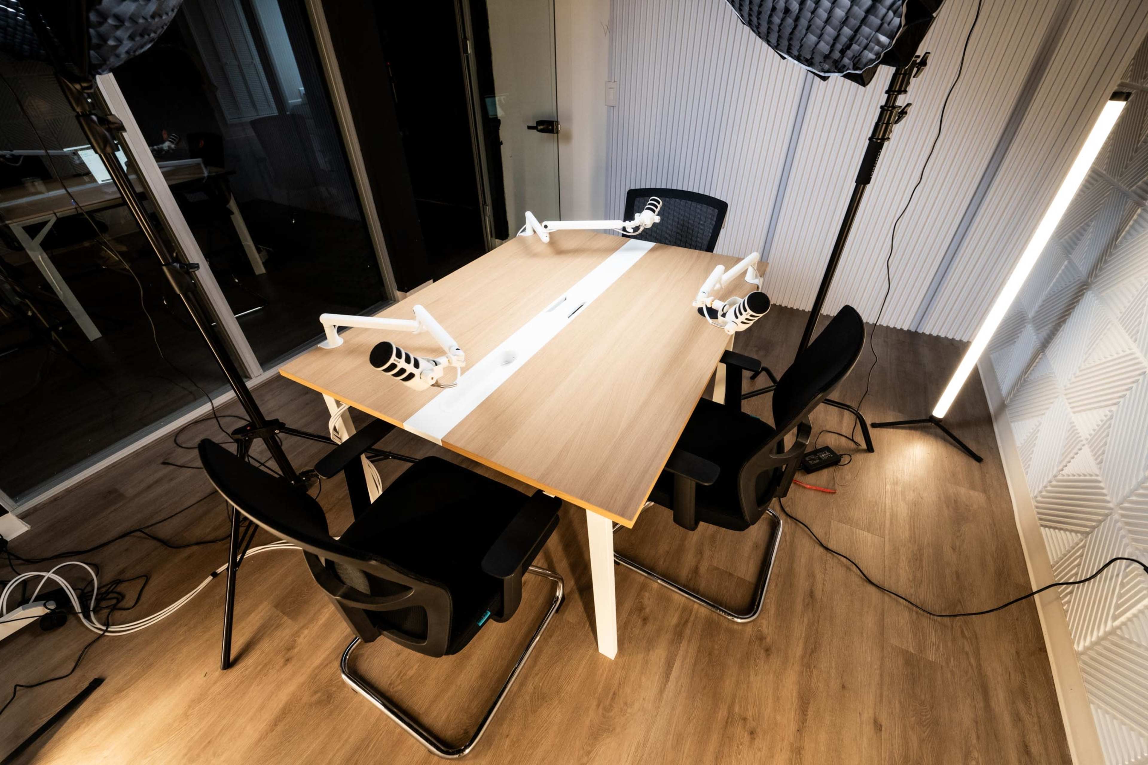 A modern work desk with two chairs and adjustable lighting equipment is set up in a well-lit room.
