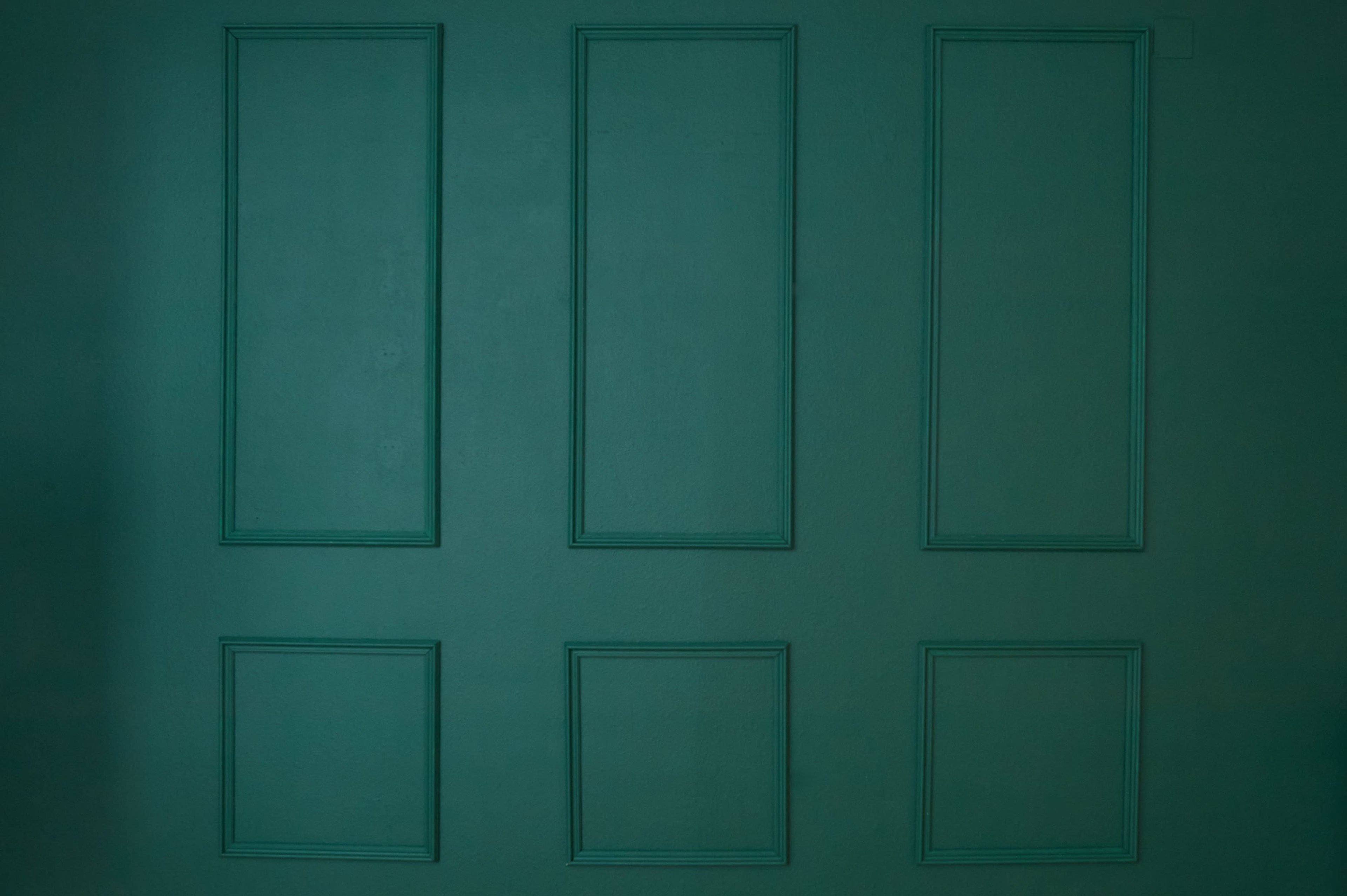 The image features a textured green wall with six framed rectangular recesses of varying sizes.