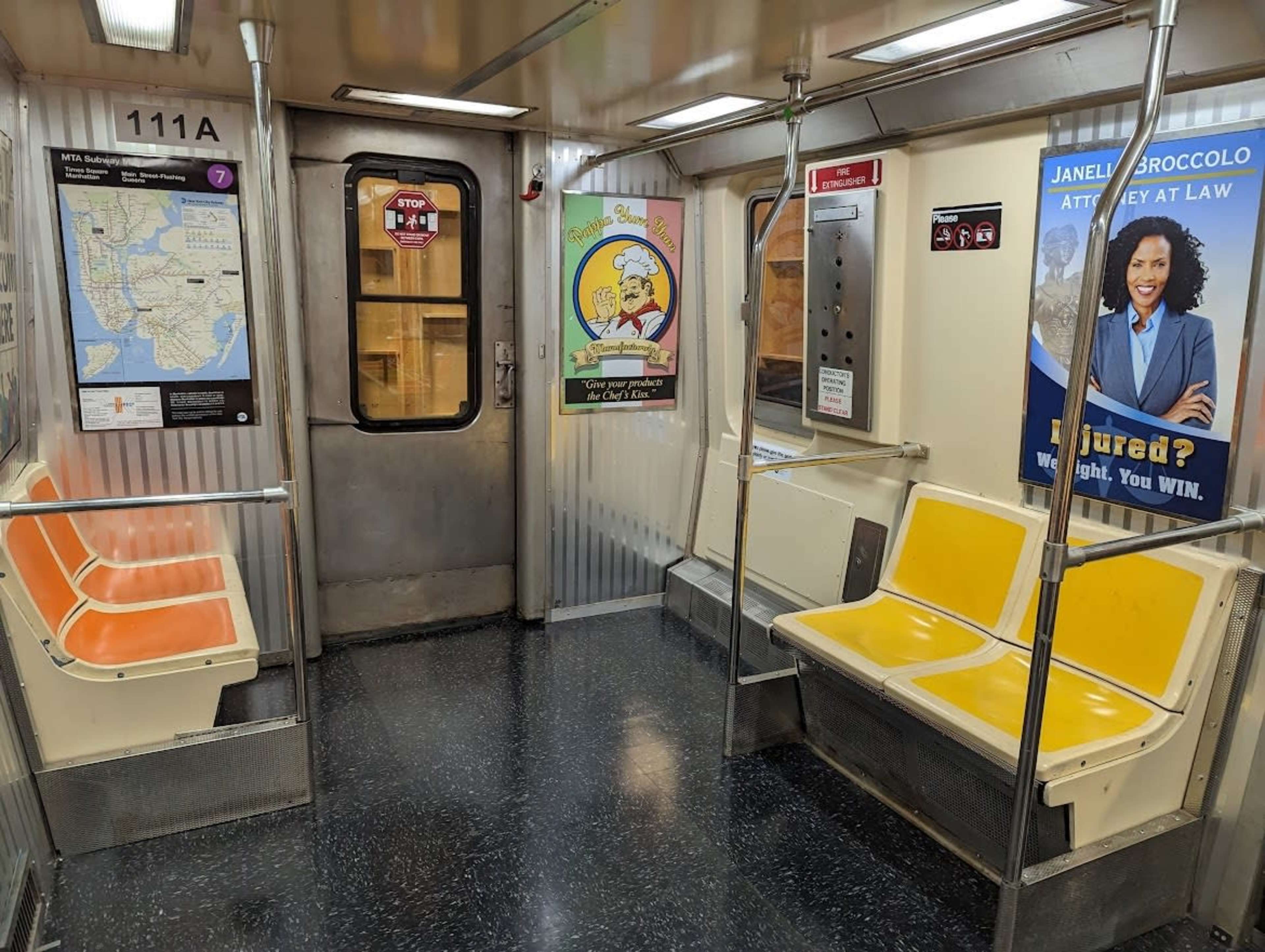 The image shows the interior of a subway train with empty orange and yellow seats, a door at one end, and various advertisements on the walls.