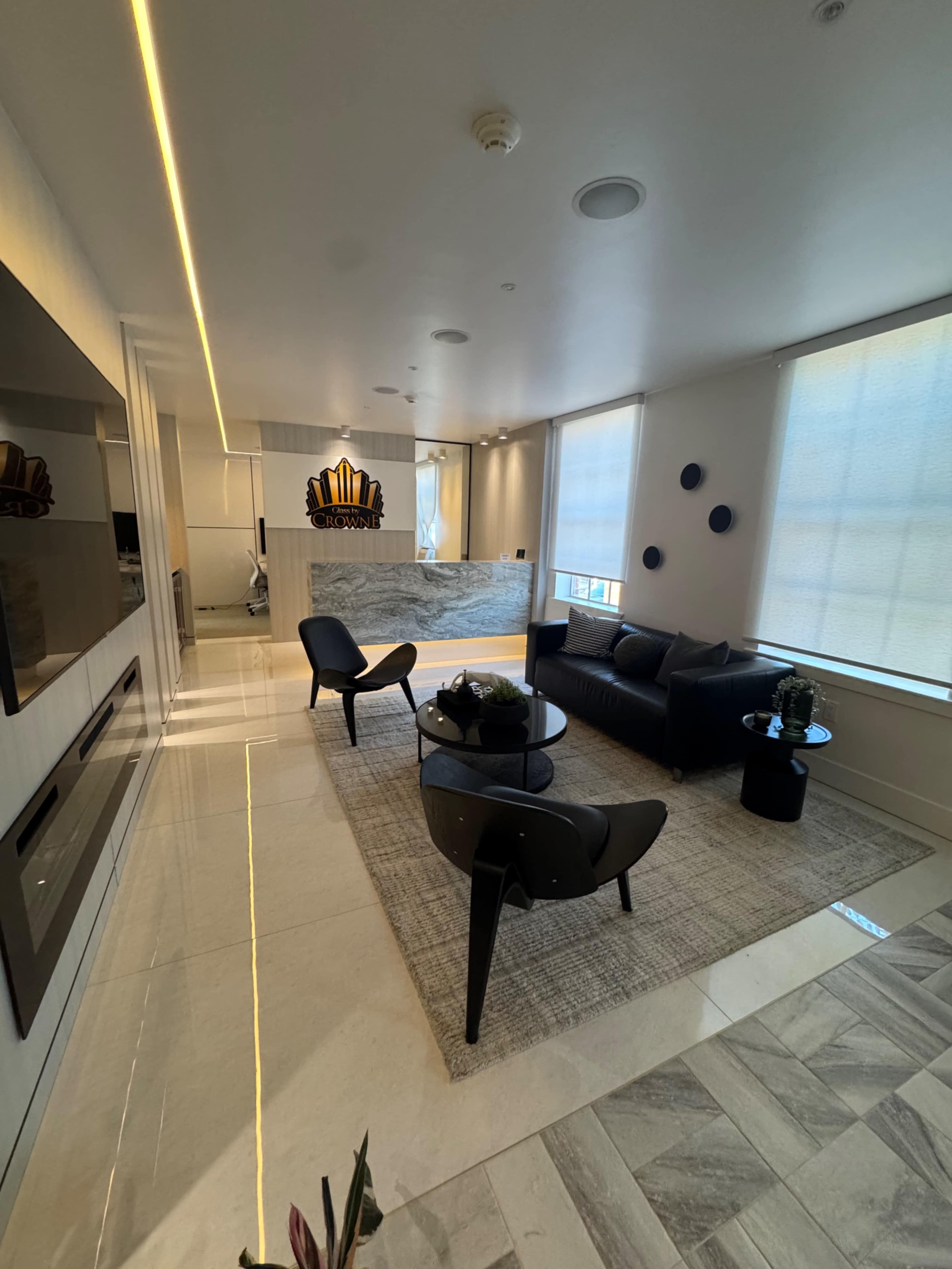 The image shows a modern reception area with a sleek desk, stylish furniture, and large windows allowing natural light to enter.