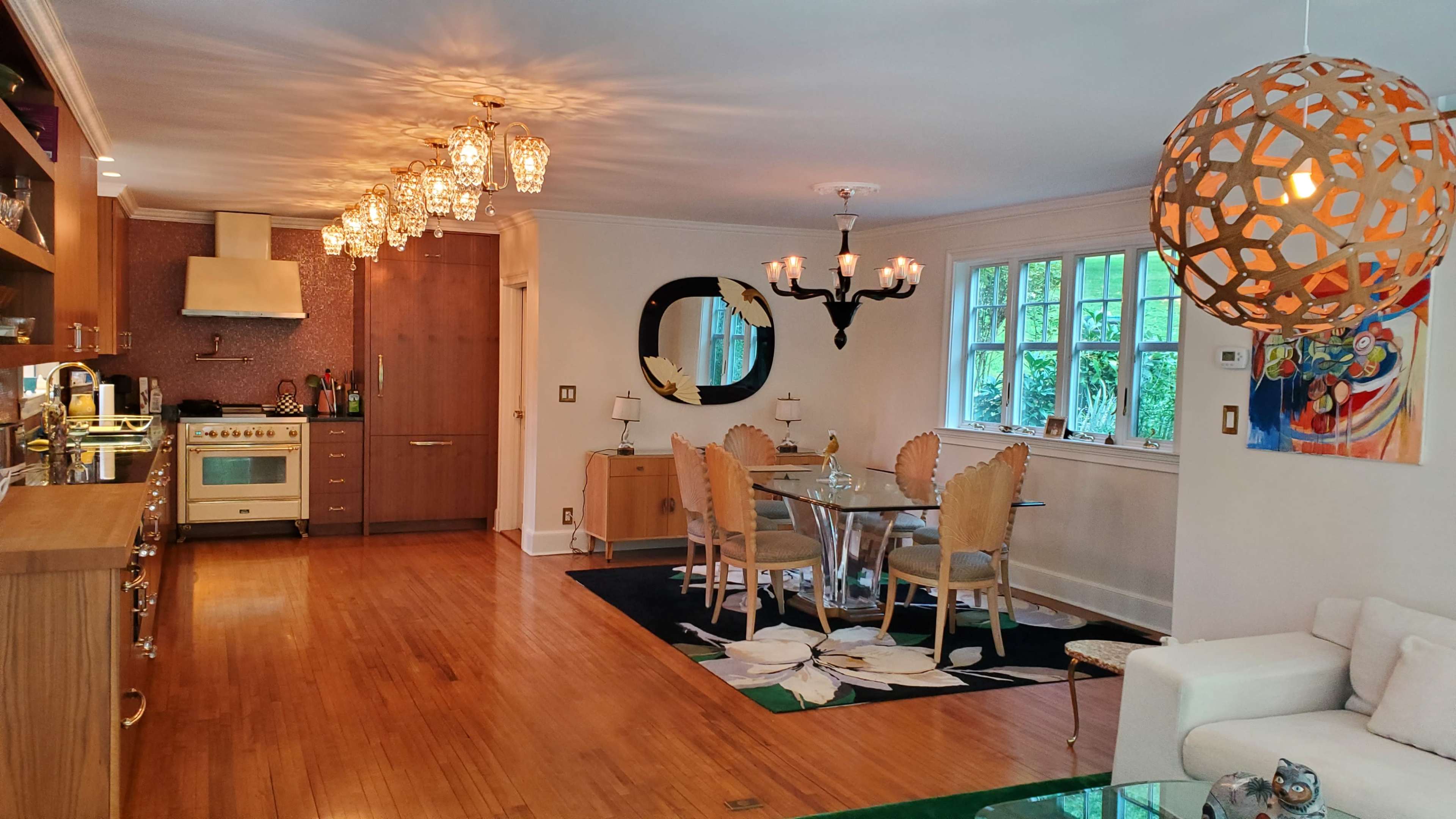 A spacious kitchen and dining area features elegant lighting, a modern chandelier, and a mix of wood and glass furniture.