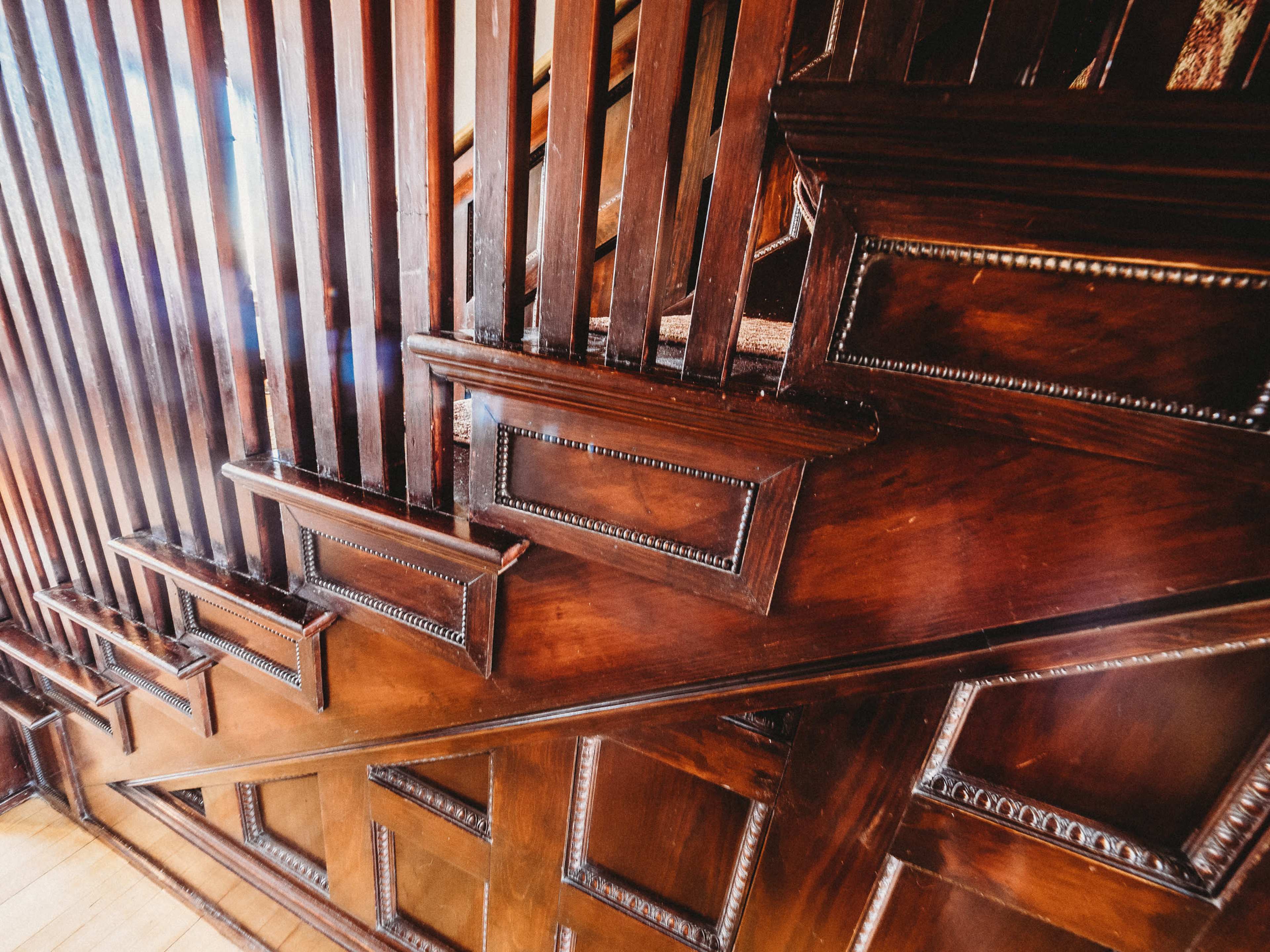 A wooden staircase with intricately designed paneling along the walls.