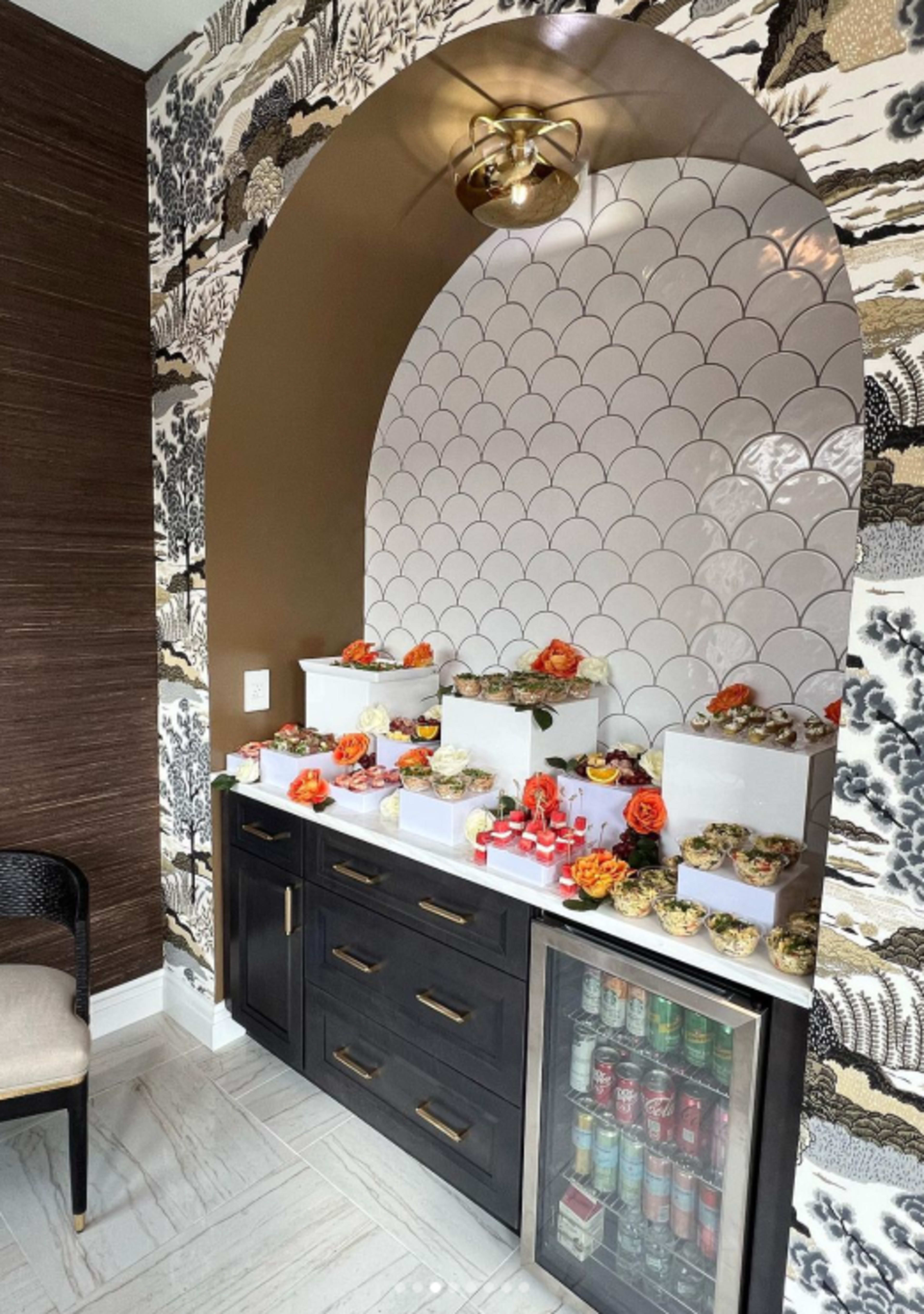 A decorative niche with several tiered displays of food arranged on a dark cabinet against a patterned wall.