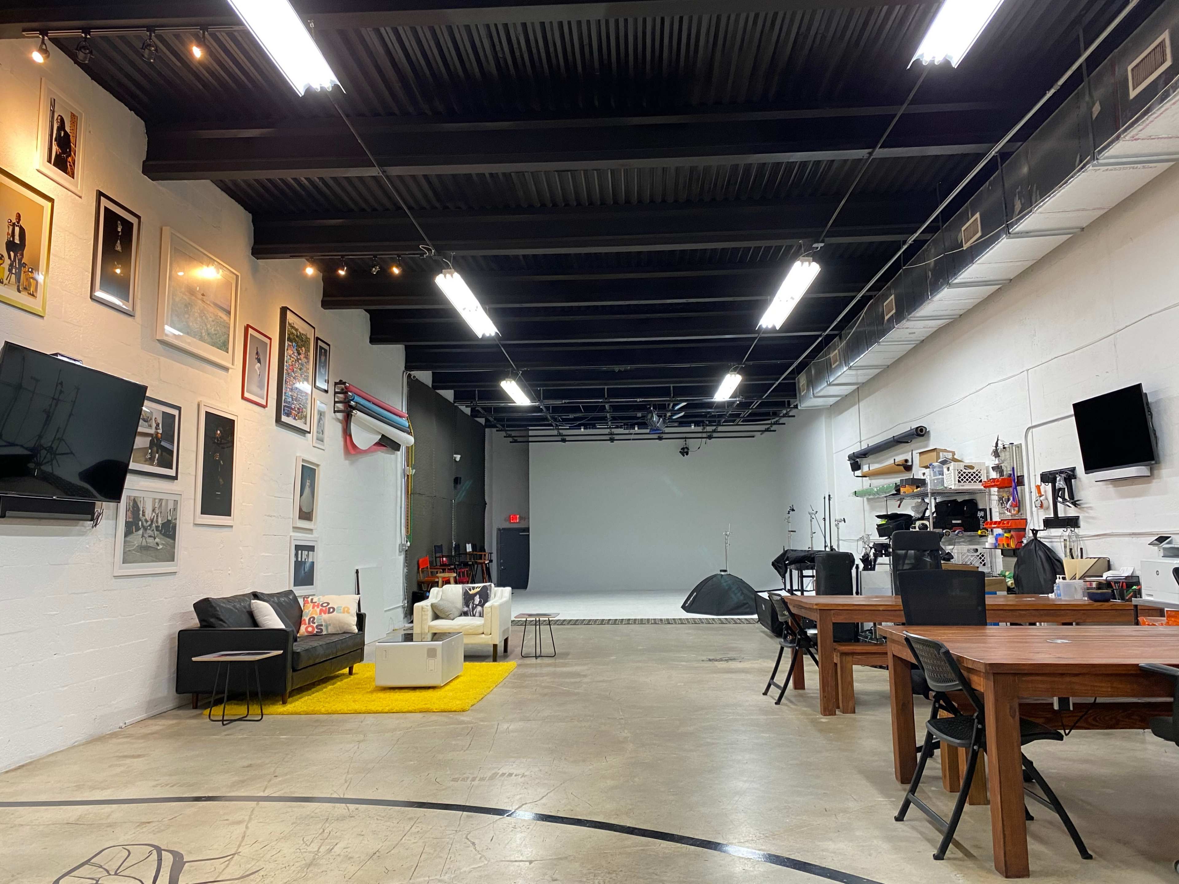 A spacious studio with art on the walls, seating areas, and various equipment arranged around a large open floor.