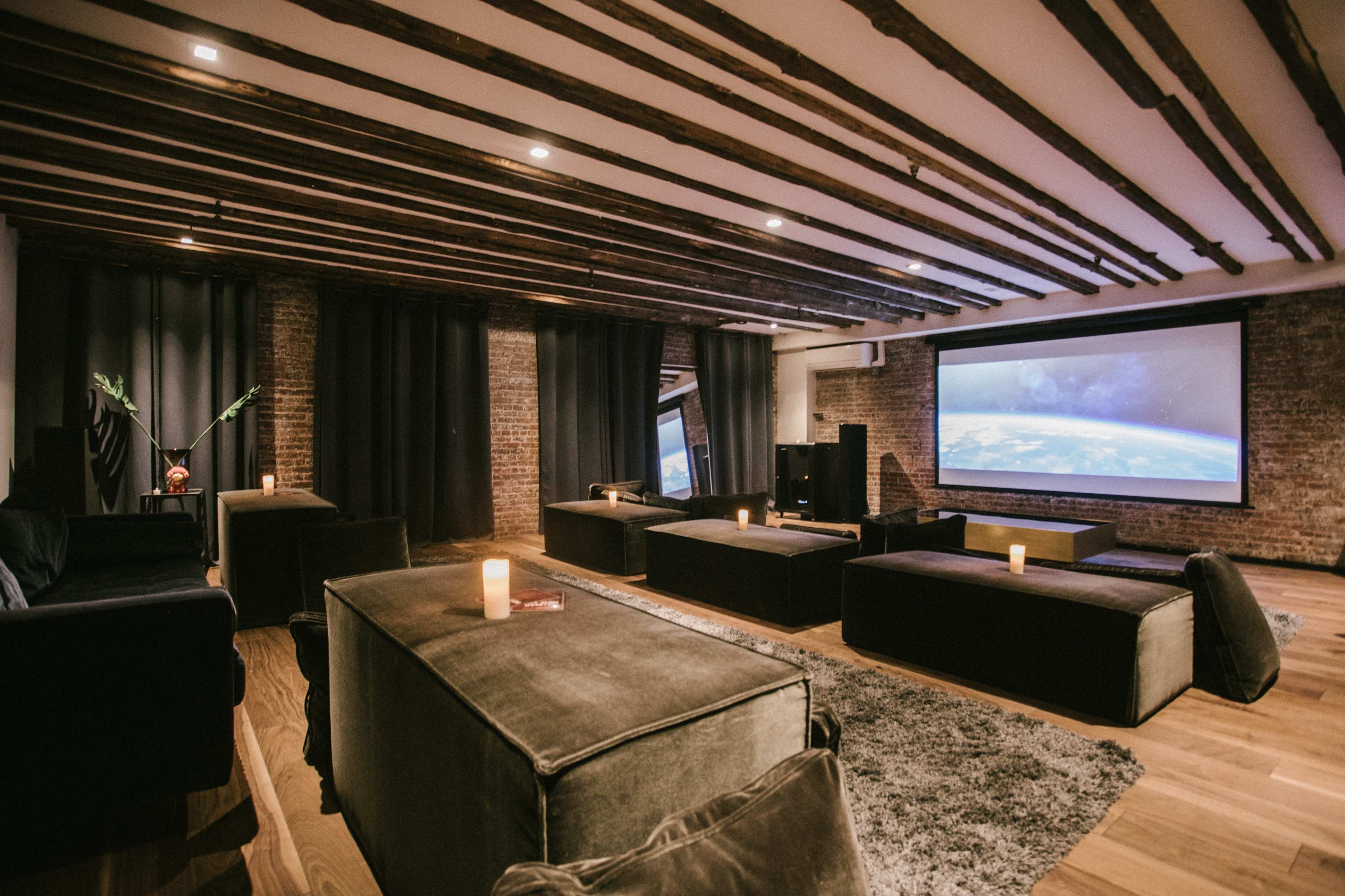 A cozy, modern home theater with a large screen, dark seating, and ambient lighting.