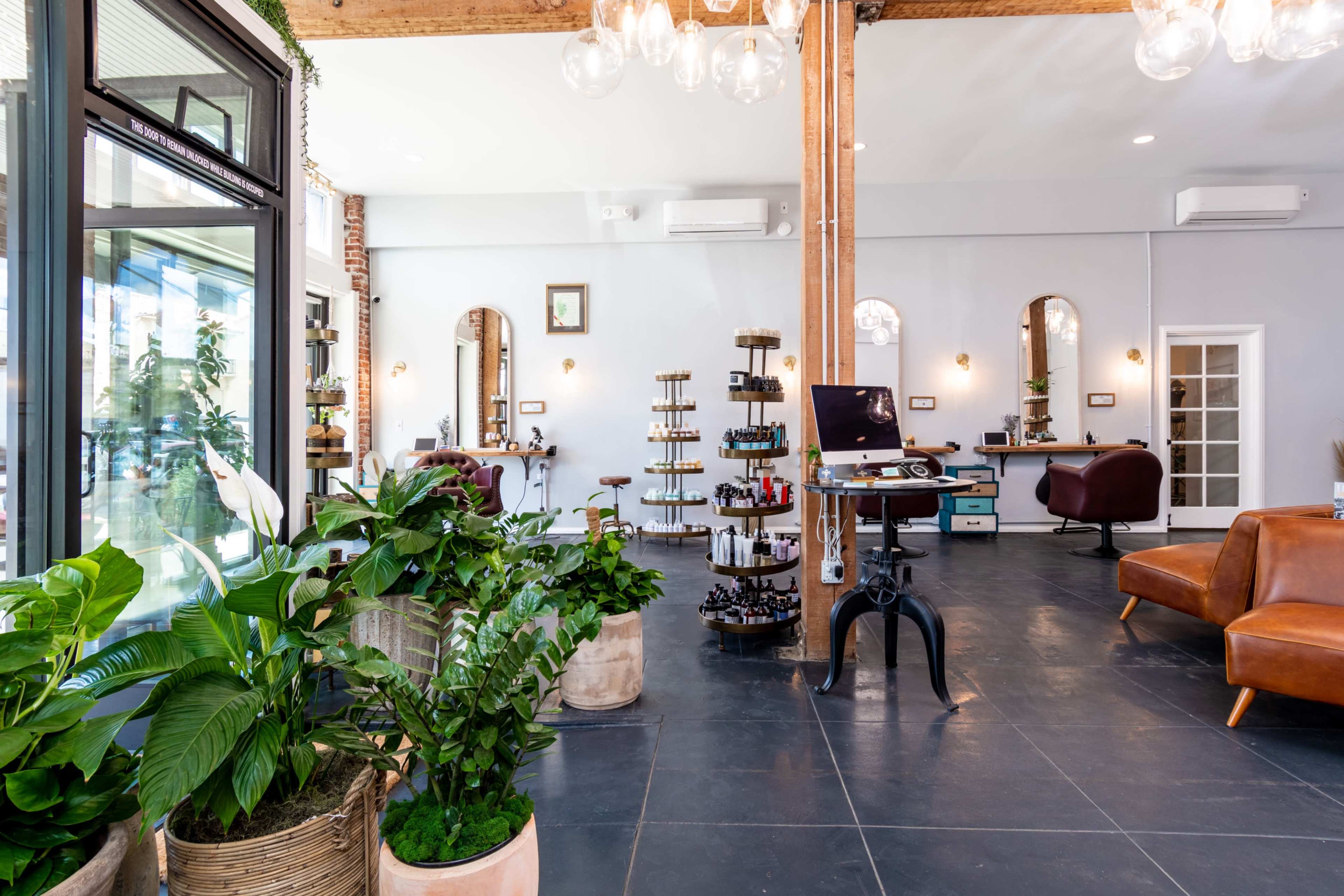 Large open gallery like salon space with brick and wood beams, high ceilings and many plants. Image in Central LA, Los Angeles, CA