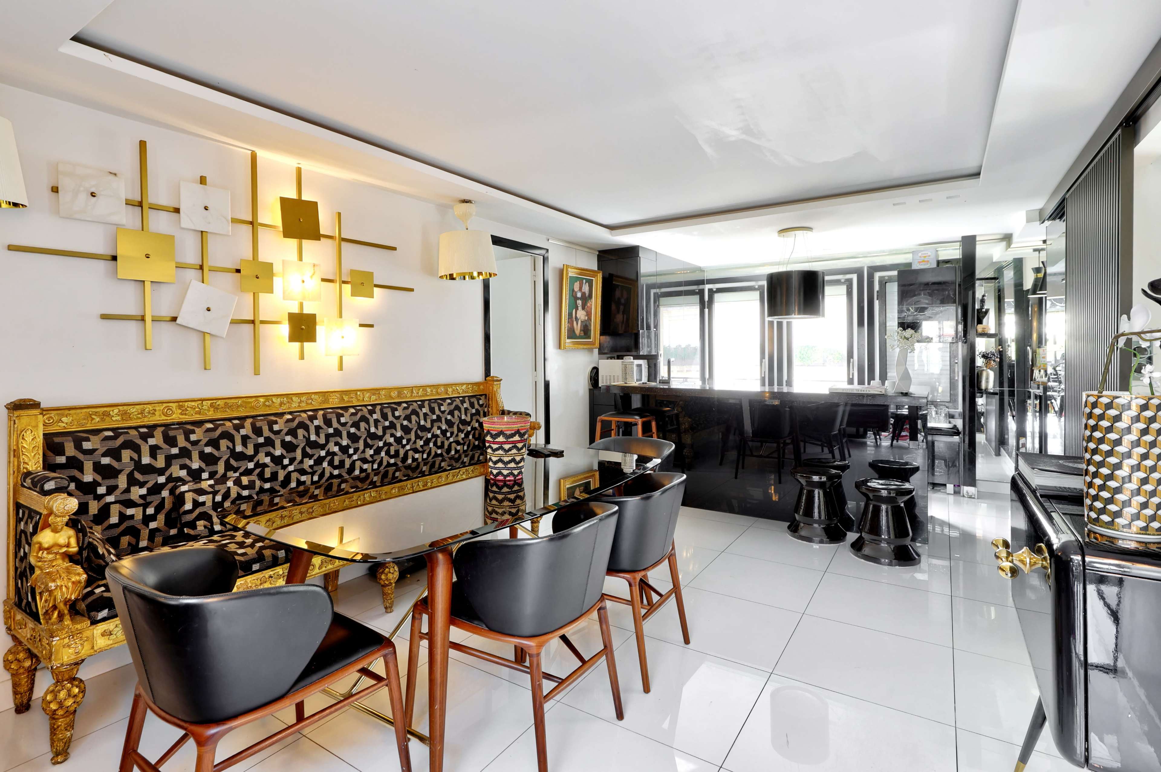 The image depicts a modern dining area with a patterned bench, black chairs, and a sleek black kitchen visible in the background.