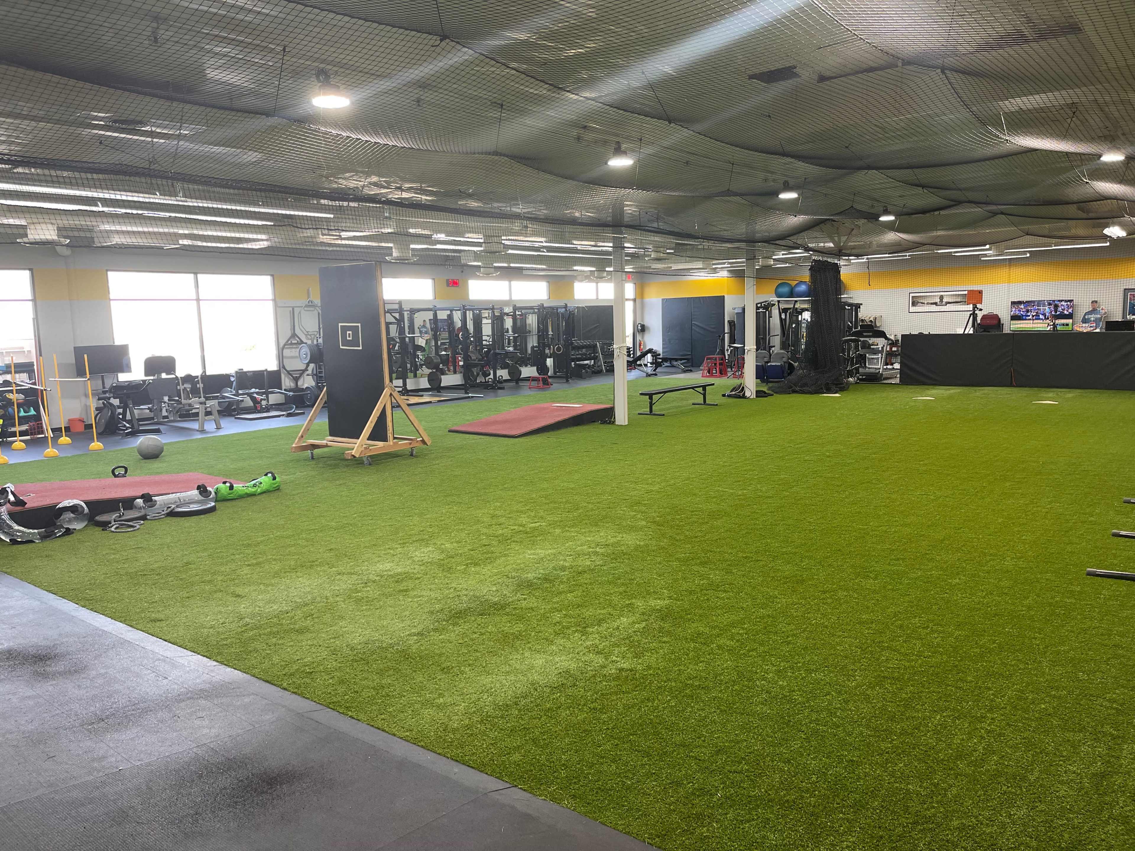 A spacious gym with artificial turf, fitness equipment, and exercise areas.