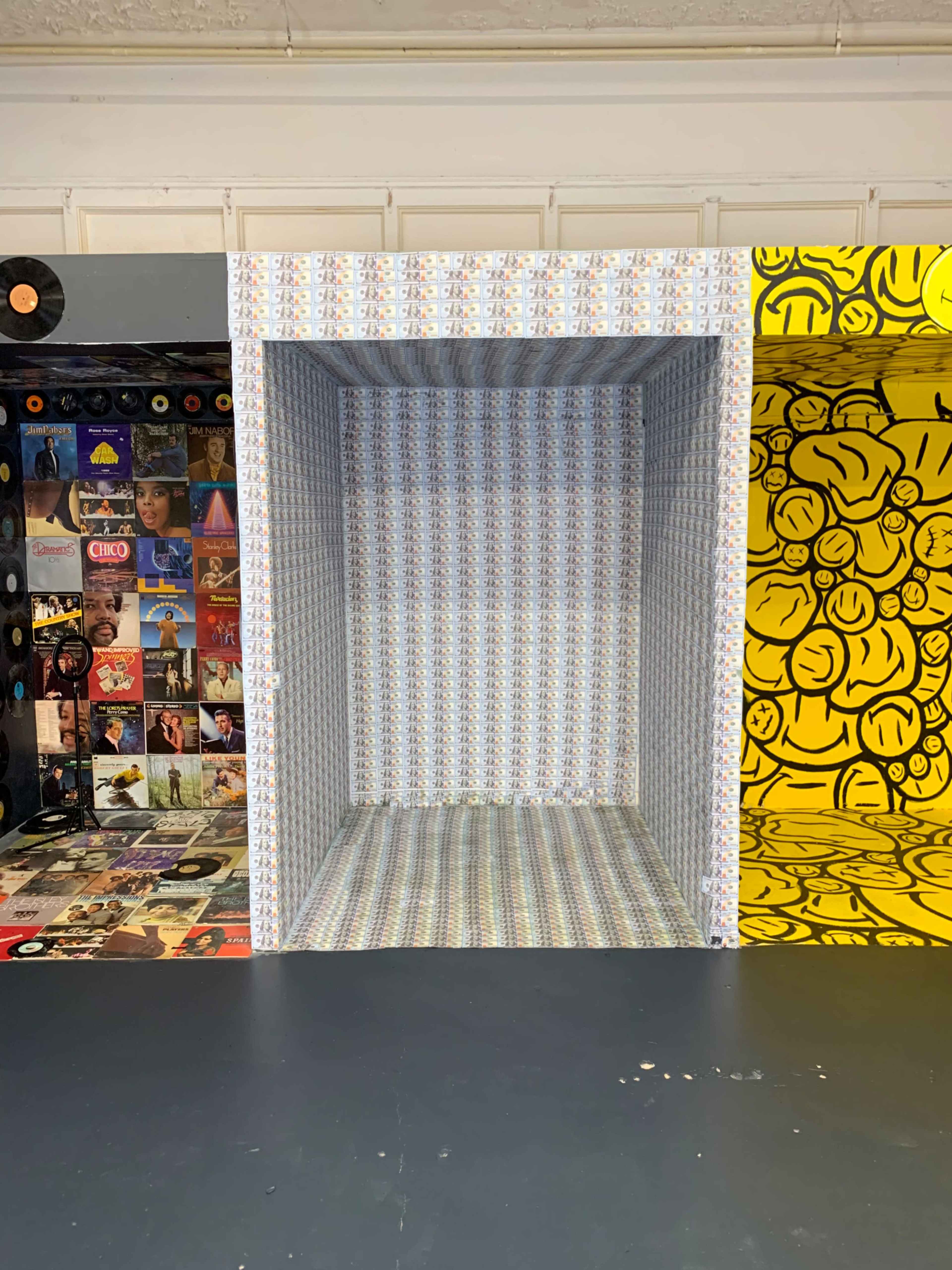 A large, empty cube-shaped space with patterned walls and a contrasting brightly colored wall covered in smiling faces on one side.