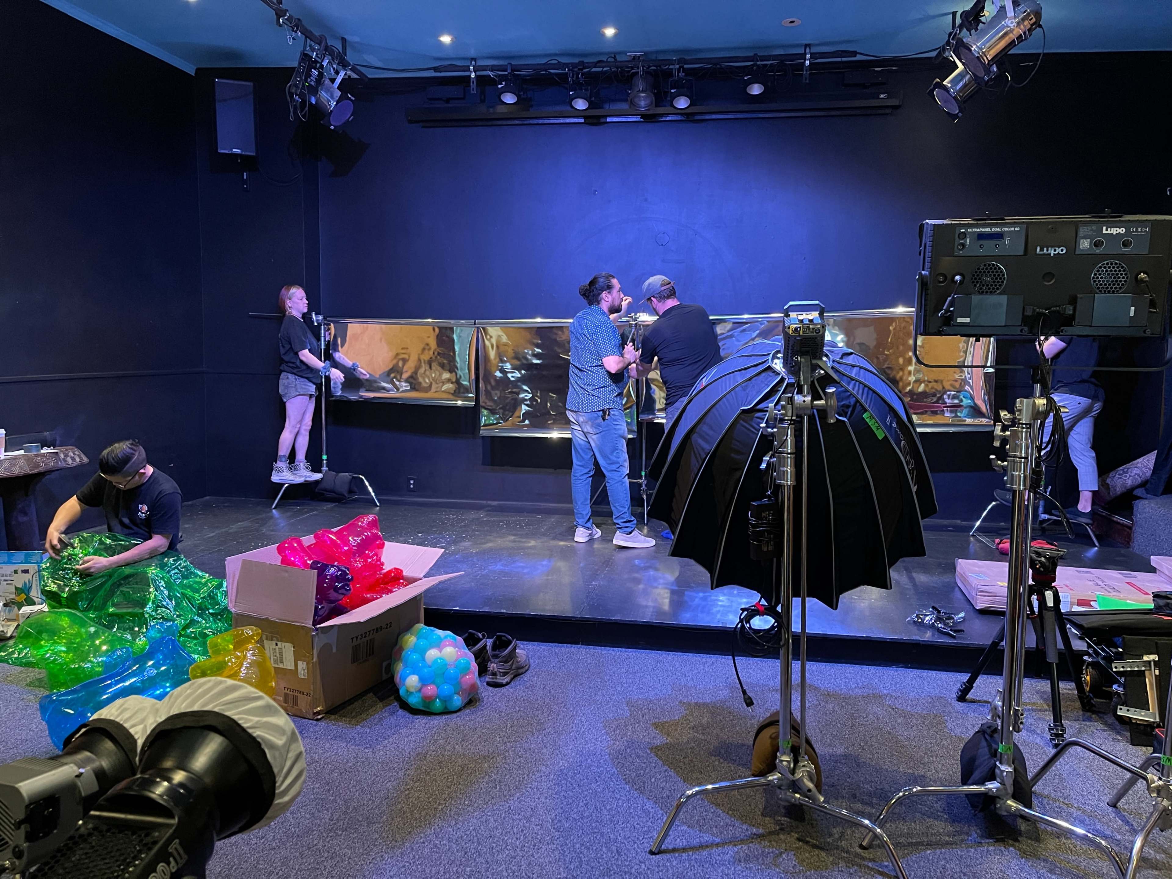 A group of individuals is setting up equipment and preparing a stage in a studio.