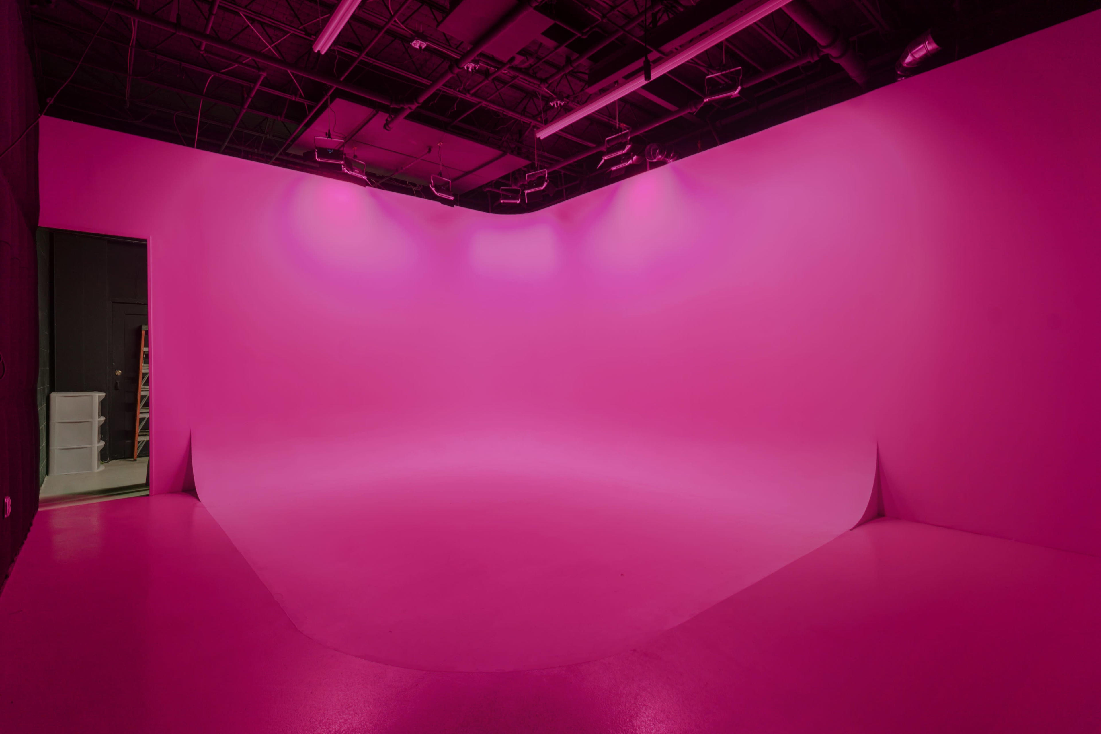 A studio with a seamless pink backdrop and a well-lit interior.