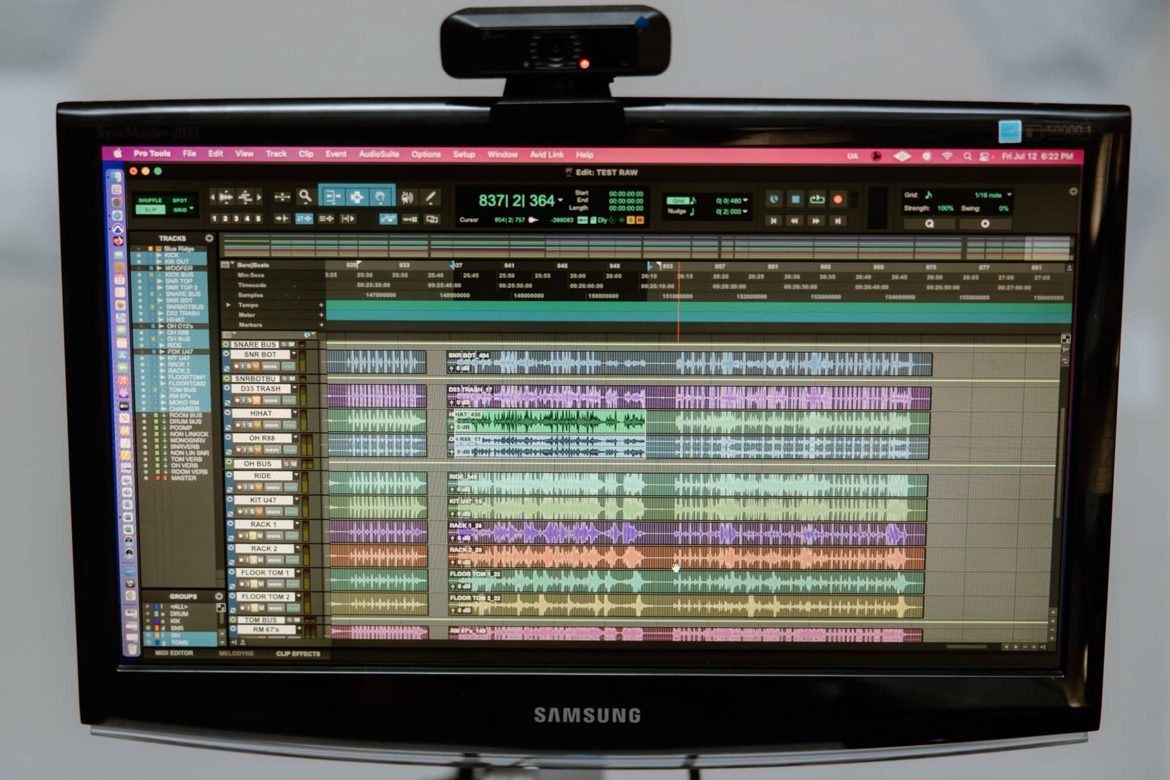 A monitor displays a digital audio workstation with multiple audio tracks arranged in a colorful, layered format.