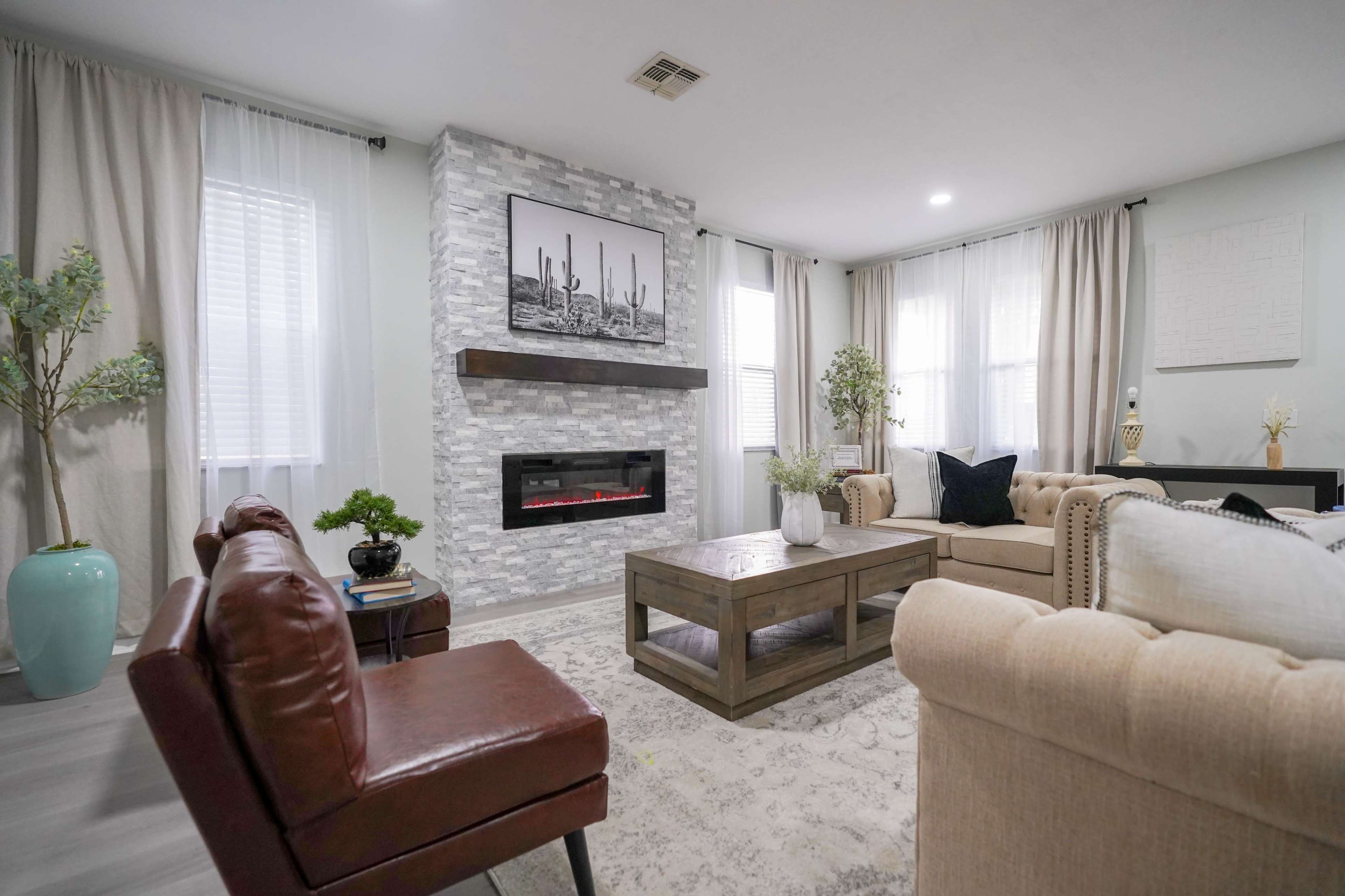 The living room features a modern design with a stone fireplace, a wooden coffee table, and comfortable seating arrangements.