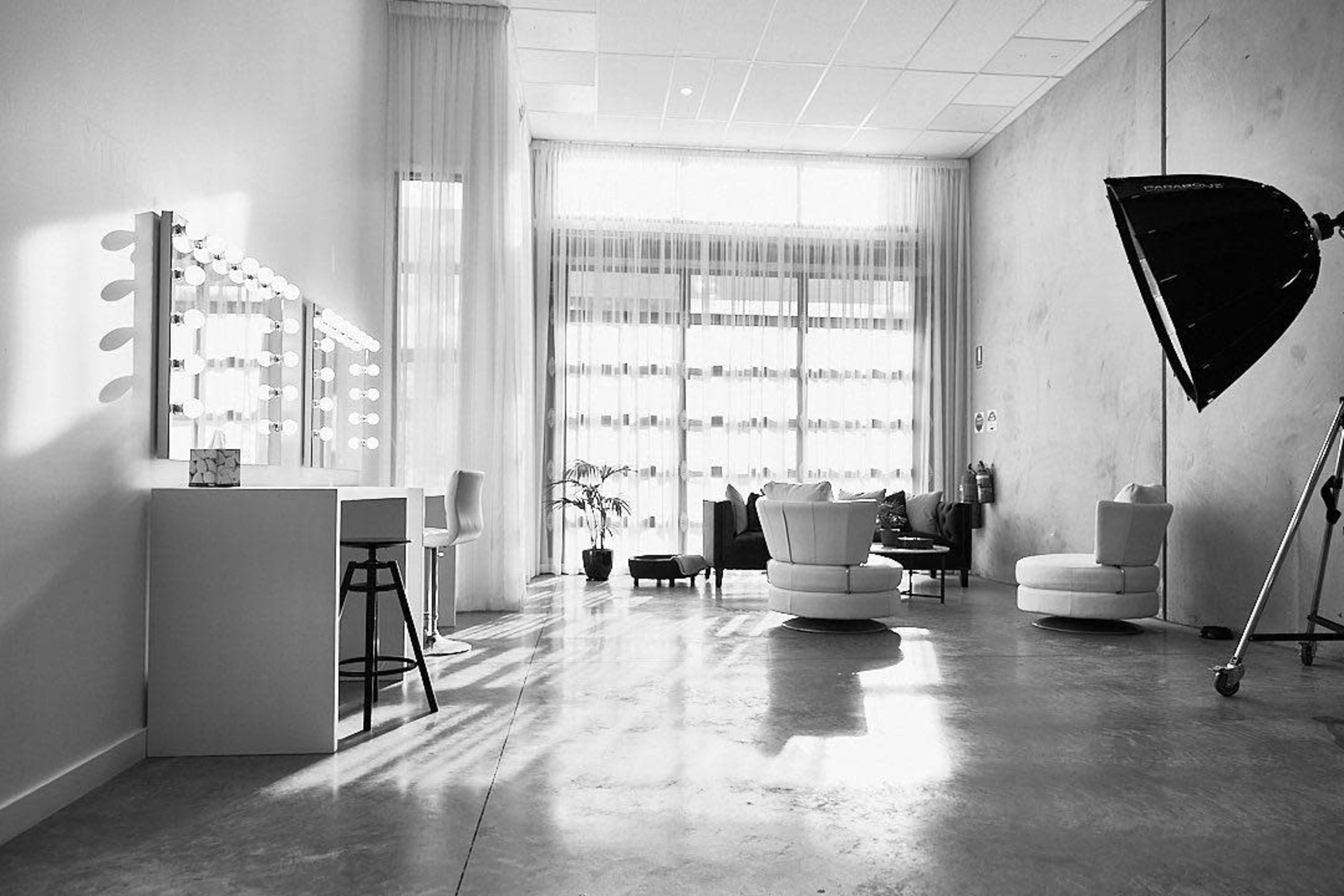 A spacious, well-lit room with a vanity mirror, comfortable seating arrangements, and large windows allowing natural light to enter.
