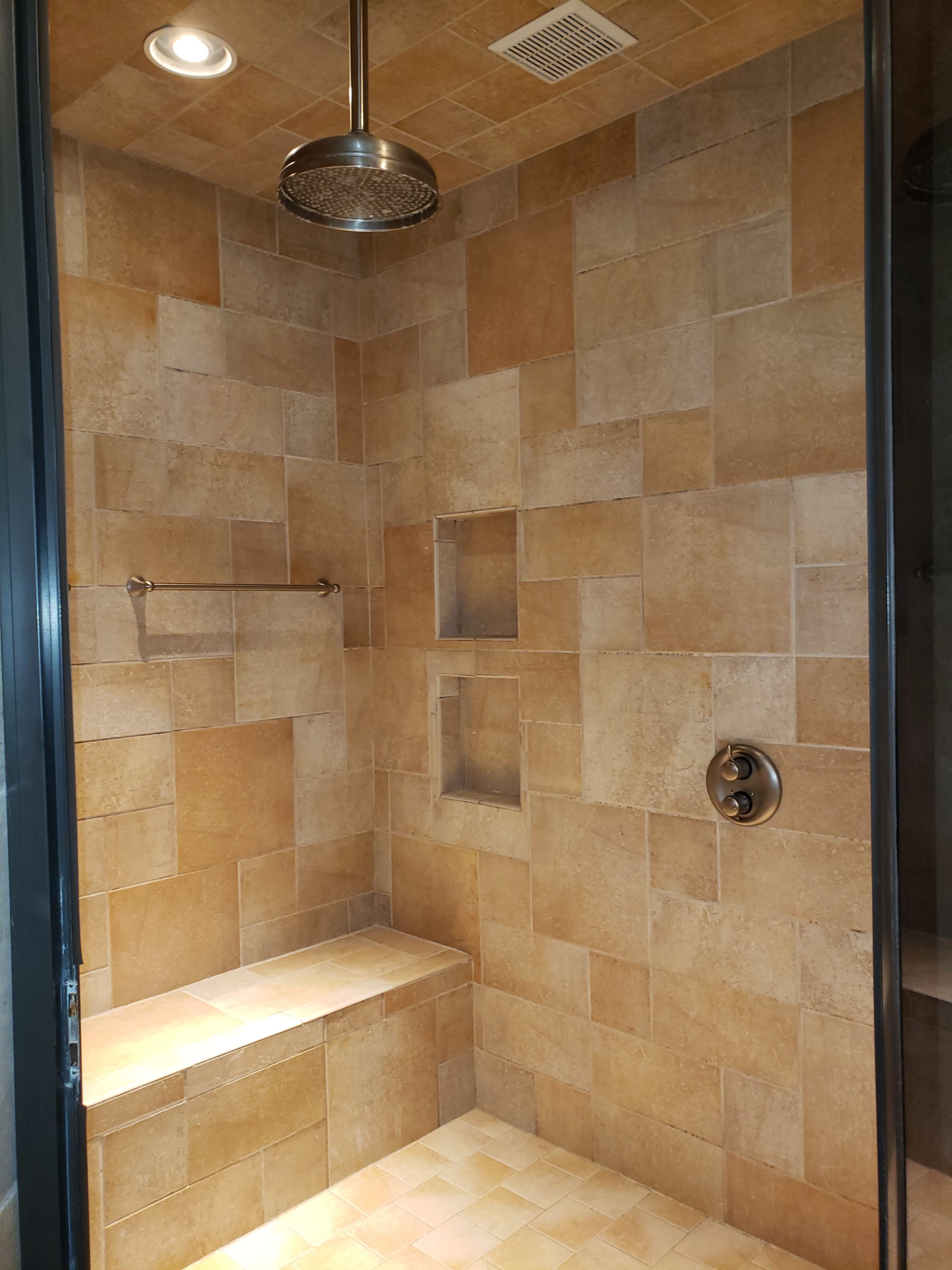 A tiled shower with a built-in bench and two recessed niches for storage.
