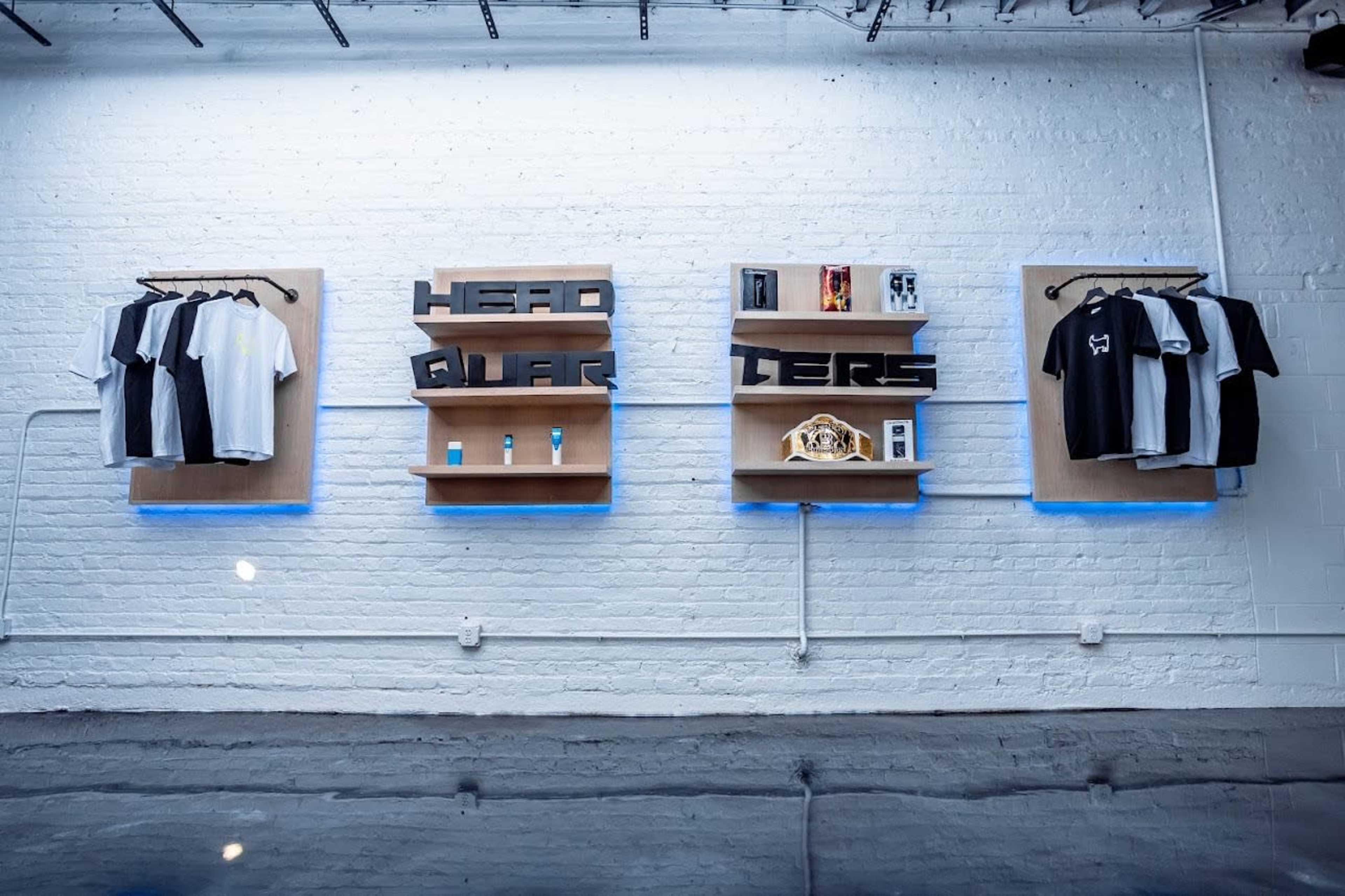 A retail display featuring clothing, accessories, and shelves labeled "HEAD QUARTERS" against a white brick wall.