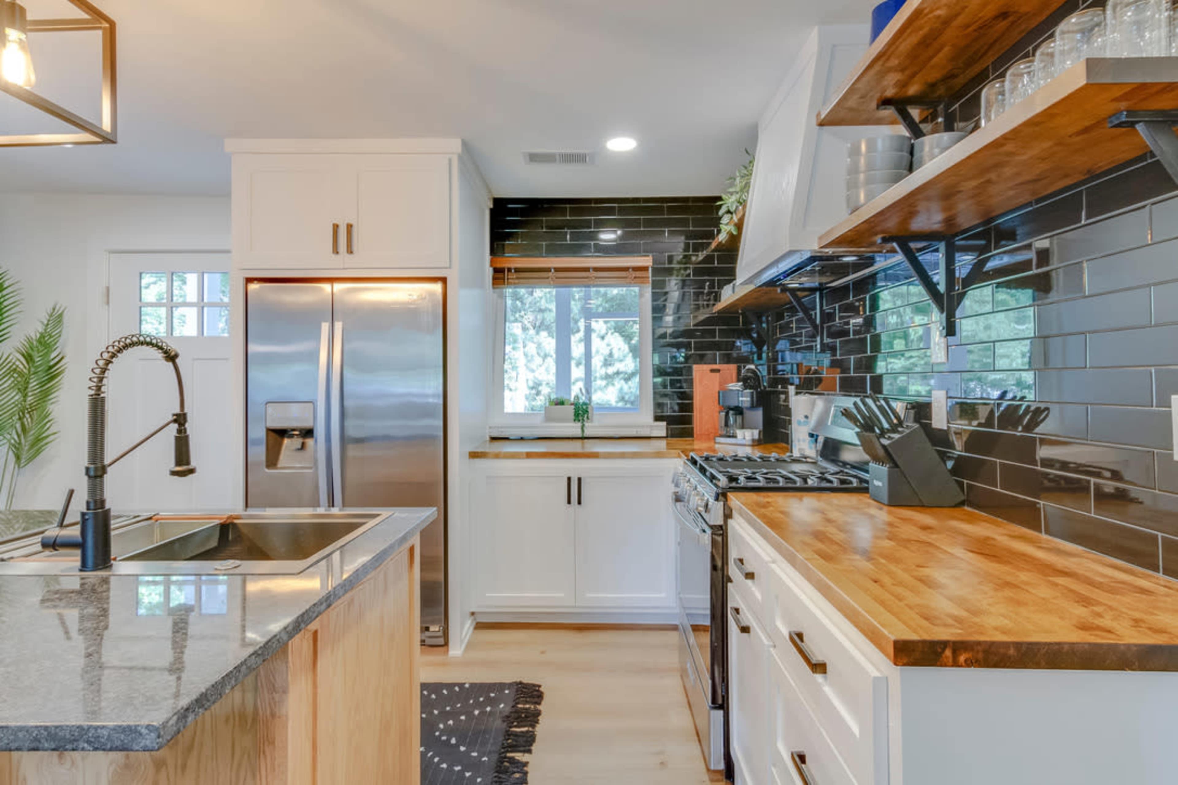 The image showcases a modern kitchen with white cabinets, stainless steel appliances, and dark tiled backsplash.