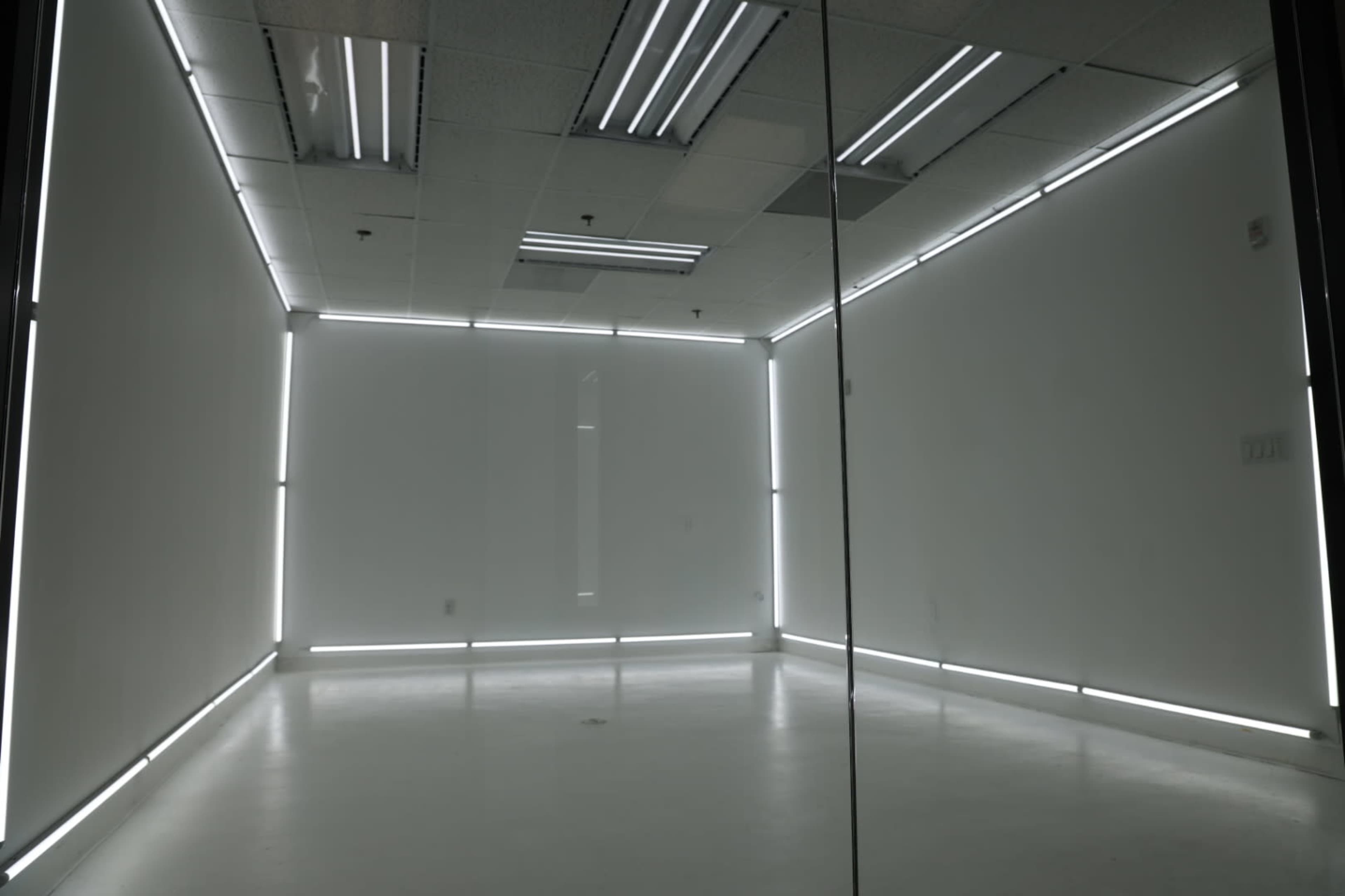 A minimalist, well-lit room with white walls and illuminated edges.