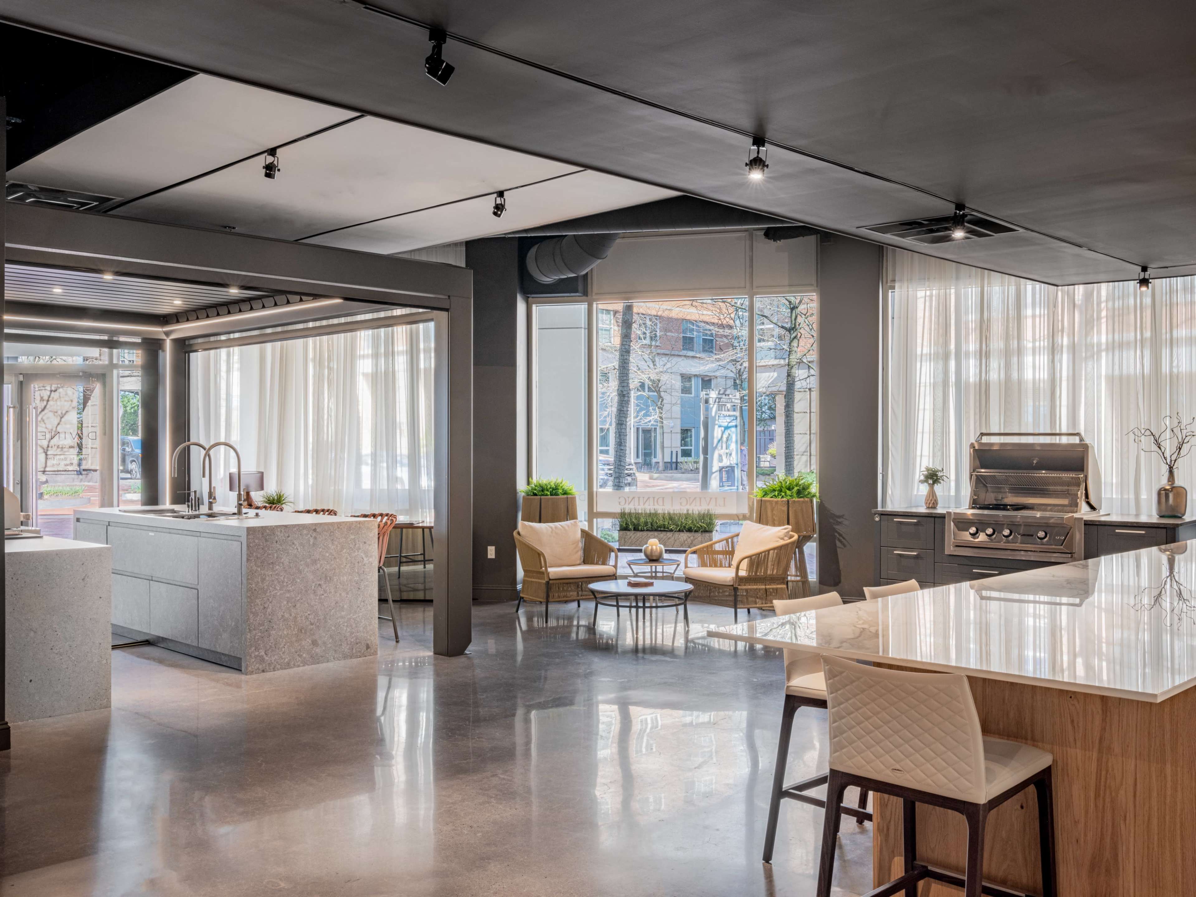 A modern kitchen and living area with sleek furniture, large windows, and a central island.