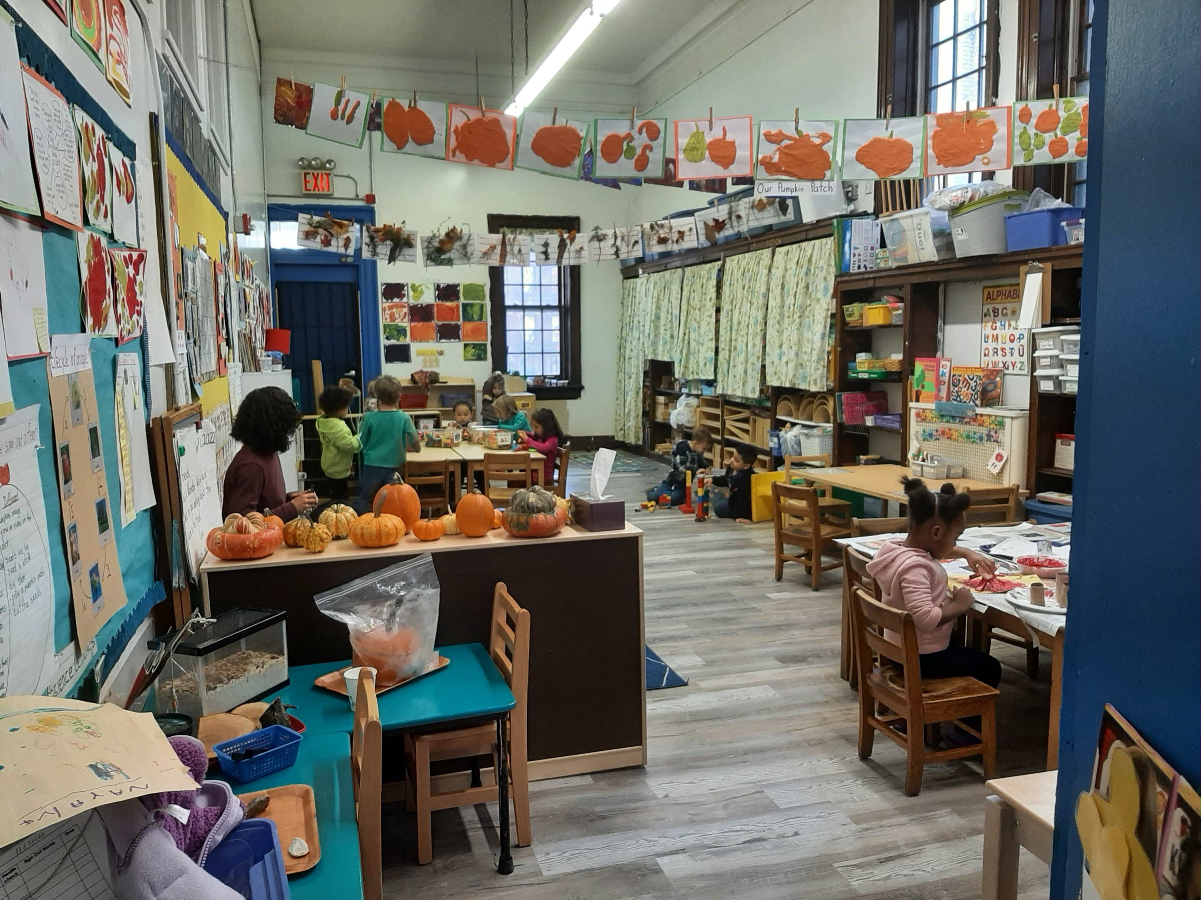 A classroom filled with children engaged in various art activities, surrounded by colorful decorations and learning materials.