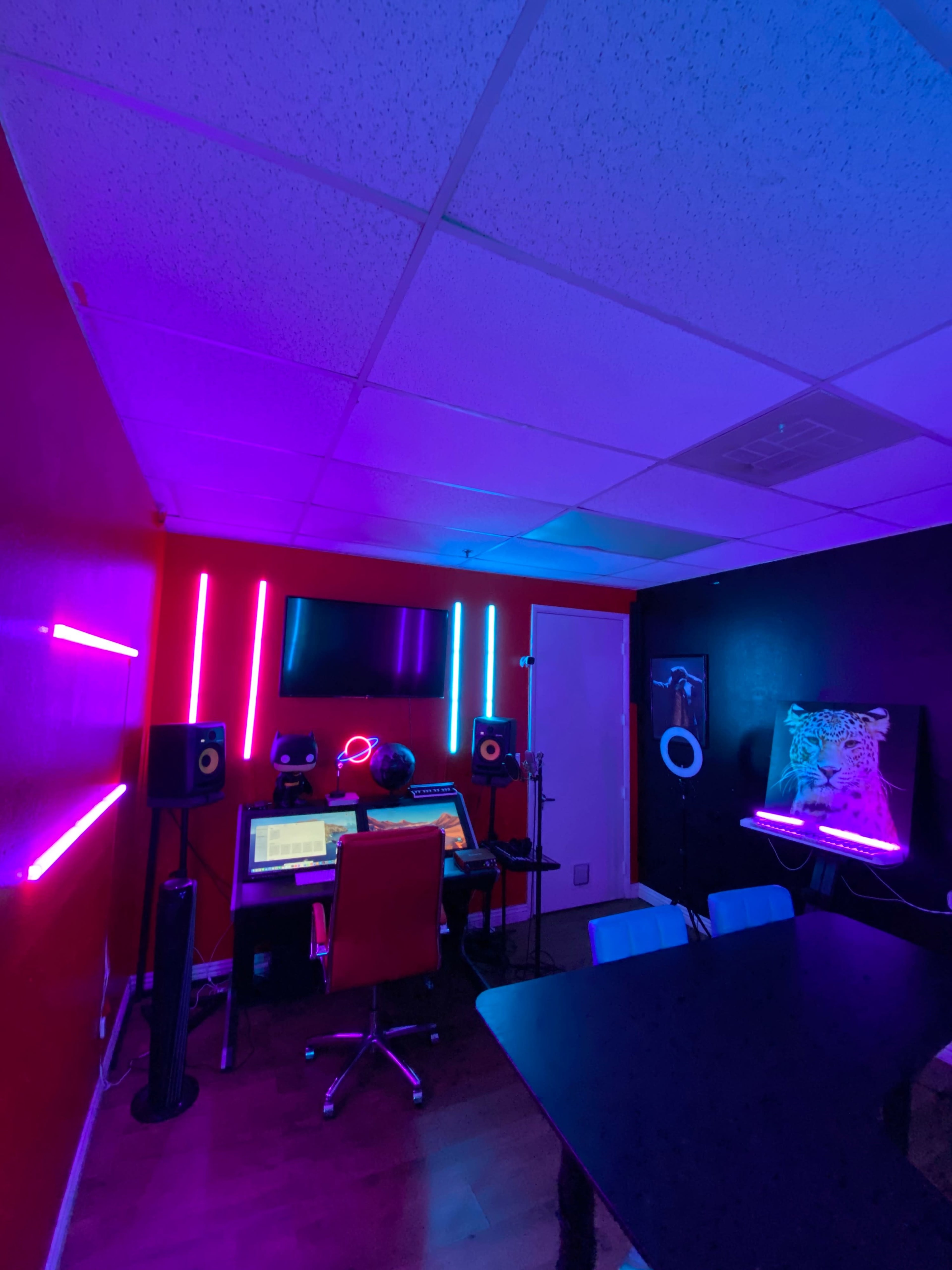 A person is seated at a desk in a music studio, surrounded by colorful LED lights and audio equipment.