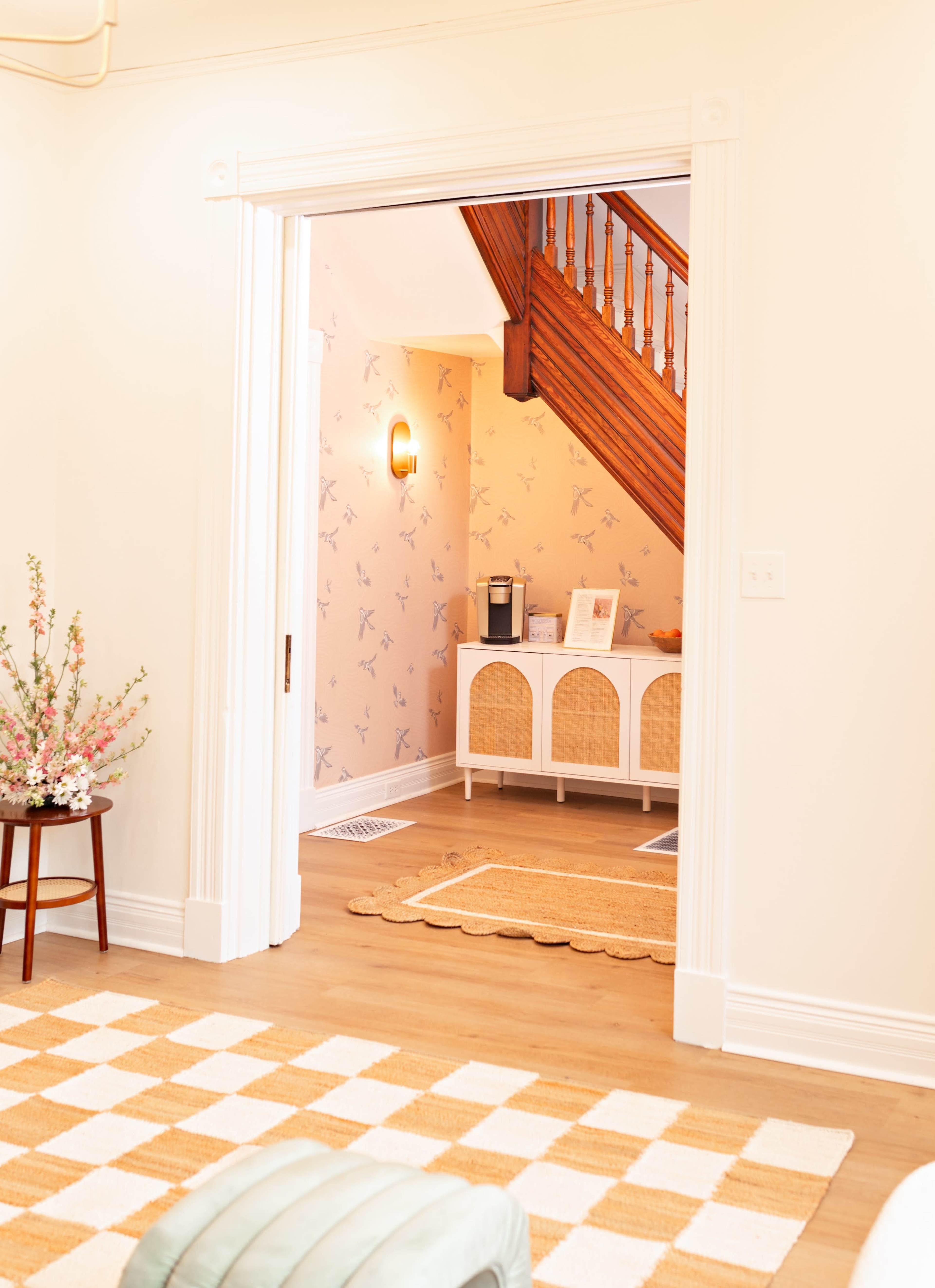 A hallway leads to a staircase with wooden steps and a wall adorned with patterned wallpaper.