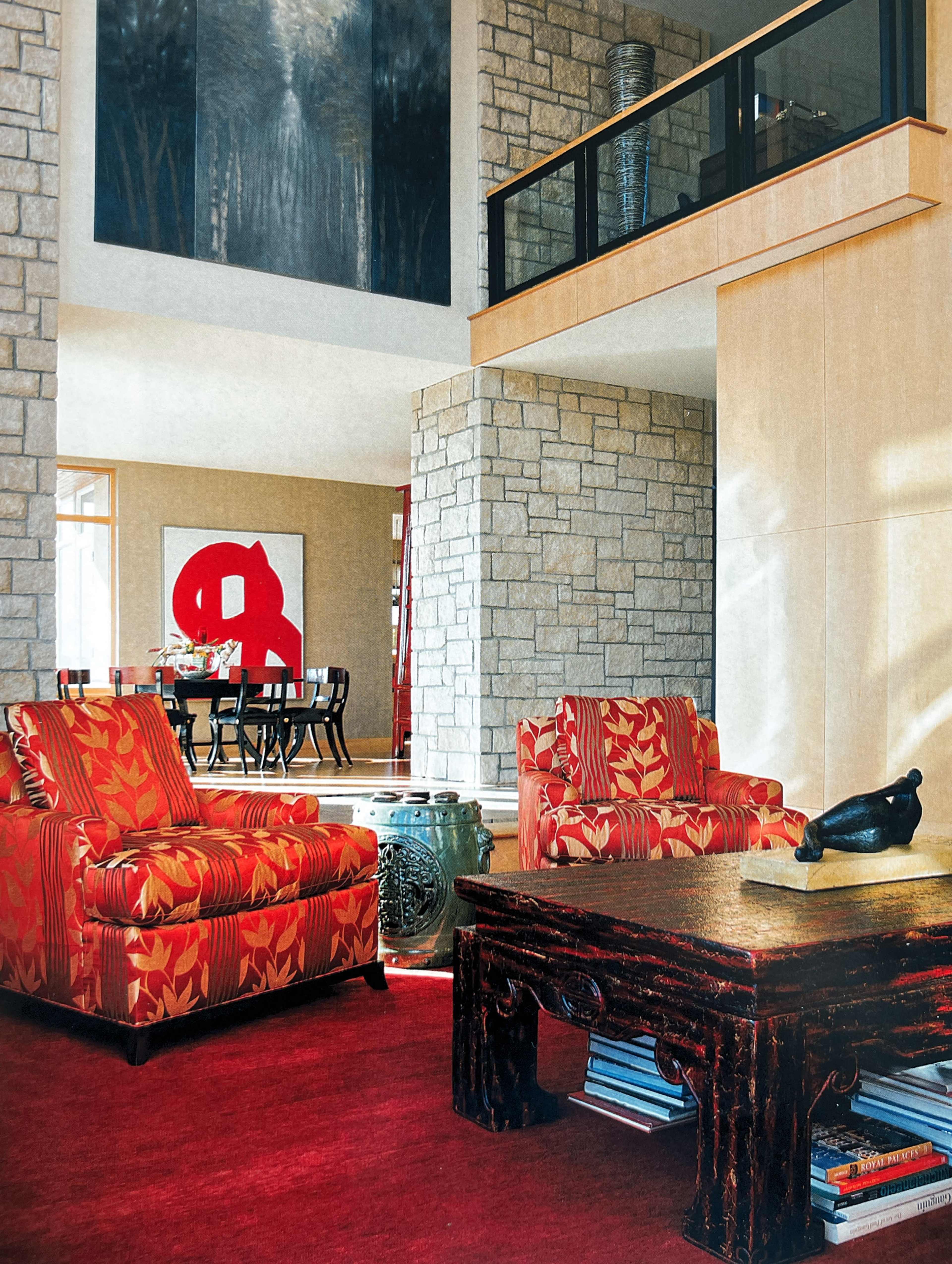 The room features two patterned armchairs, a dark wooden coffee table, and a large artwork displaying a red figure on the wall.