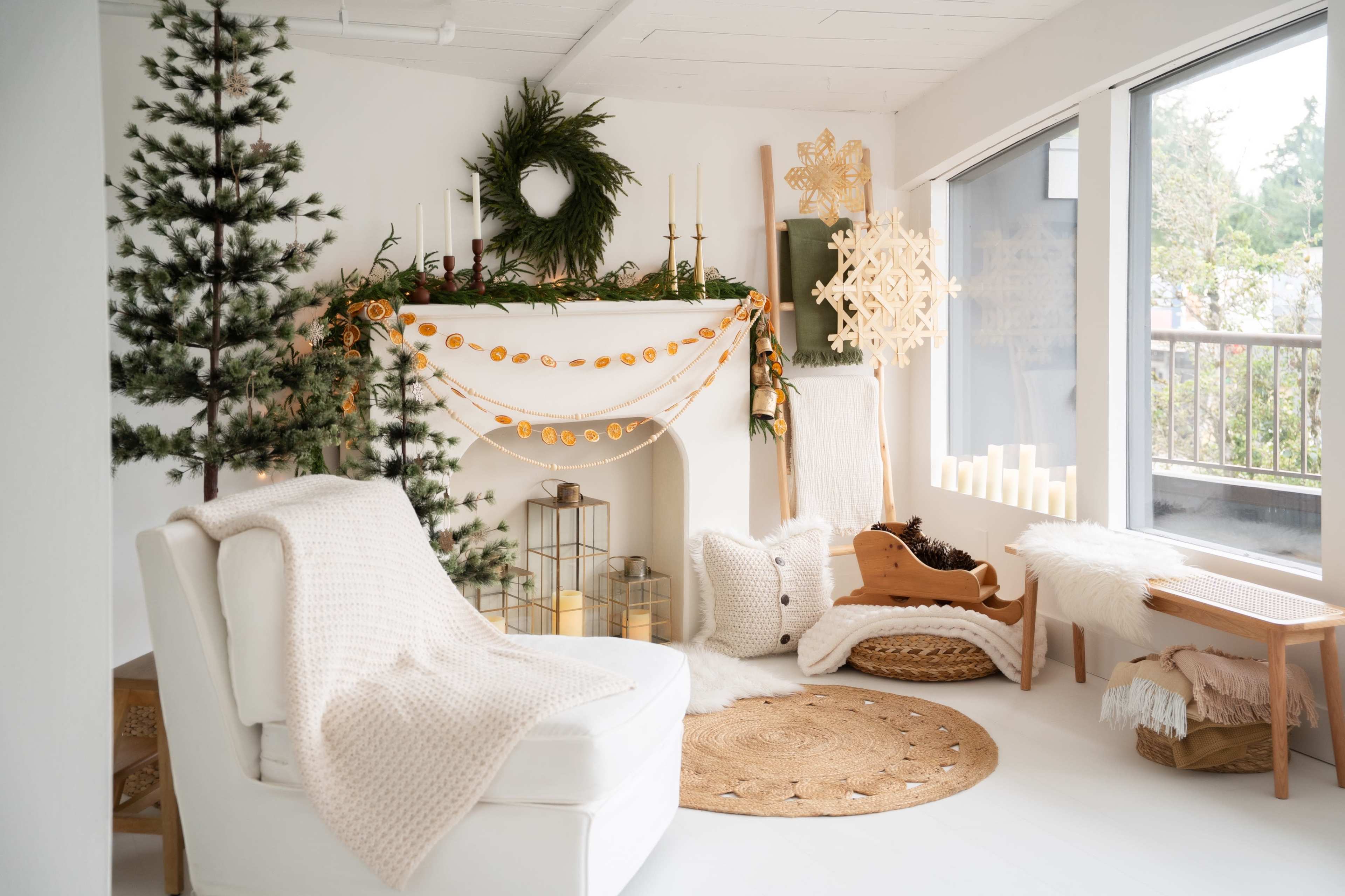 The image shows a cozy living room decorated for the holidays, featuring a white fireplace adorned with garlands, a Christmas tree, and various decorative elements scattered throughout the space.