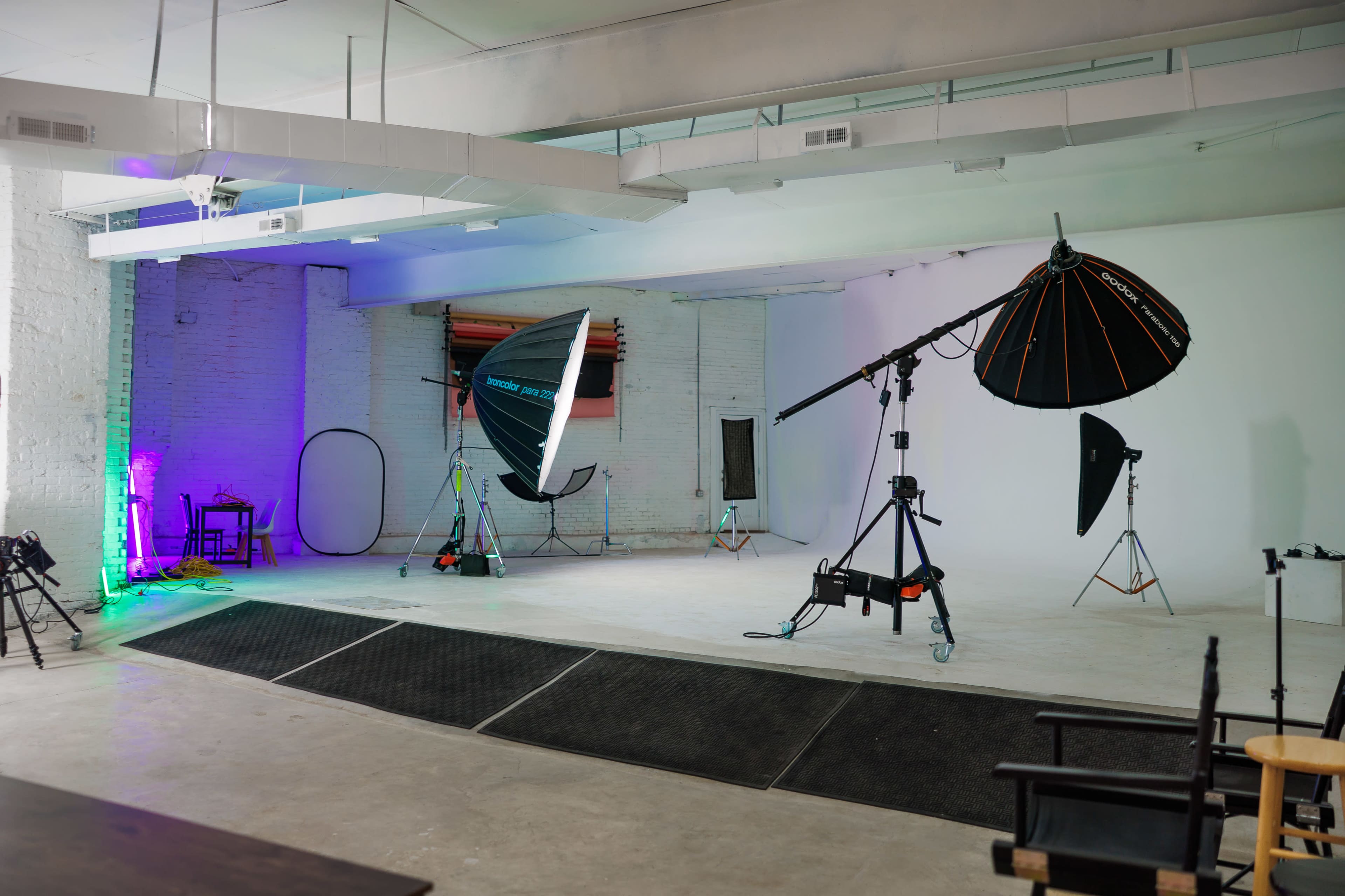 The image shows a spacious photography studio equipped with various lighting setups and backdrops.