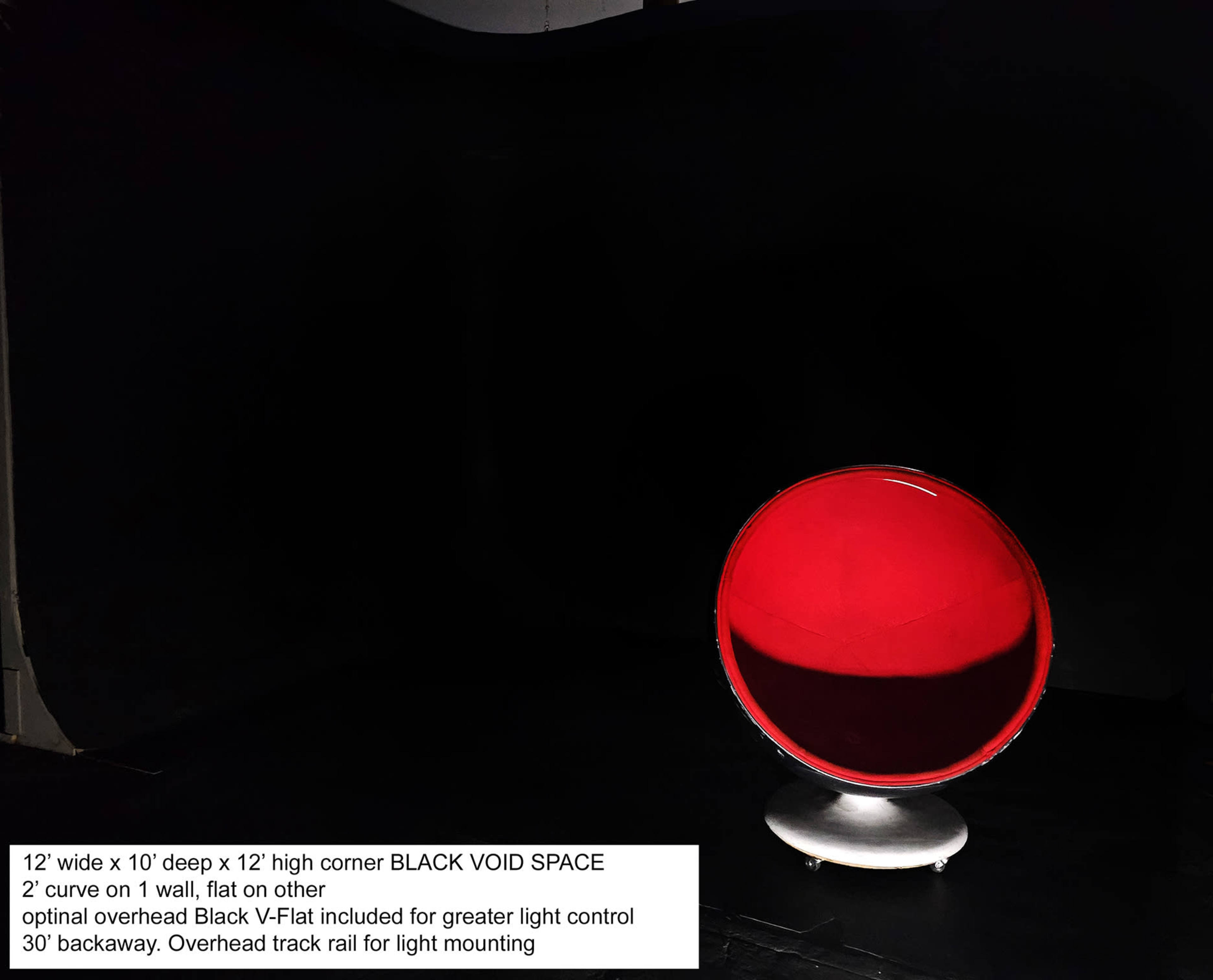 A black void space with a red circular object on a silver stand in the center, surrounded by dark walls.