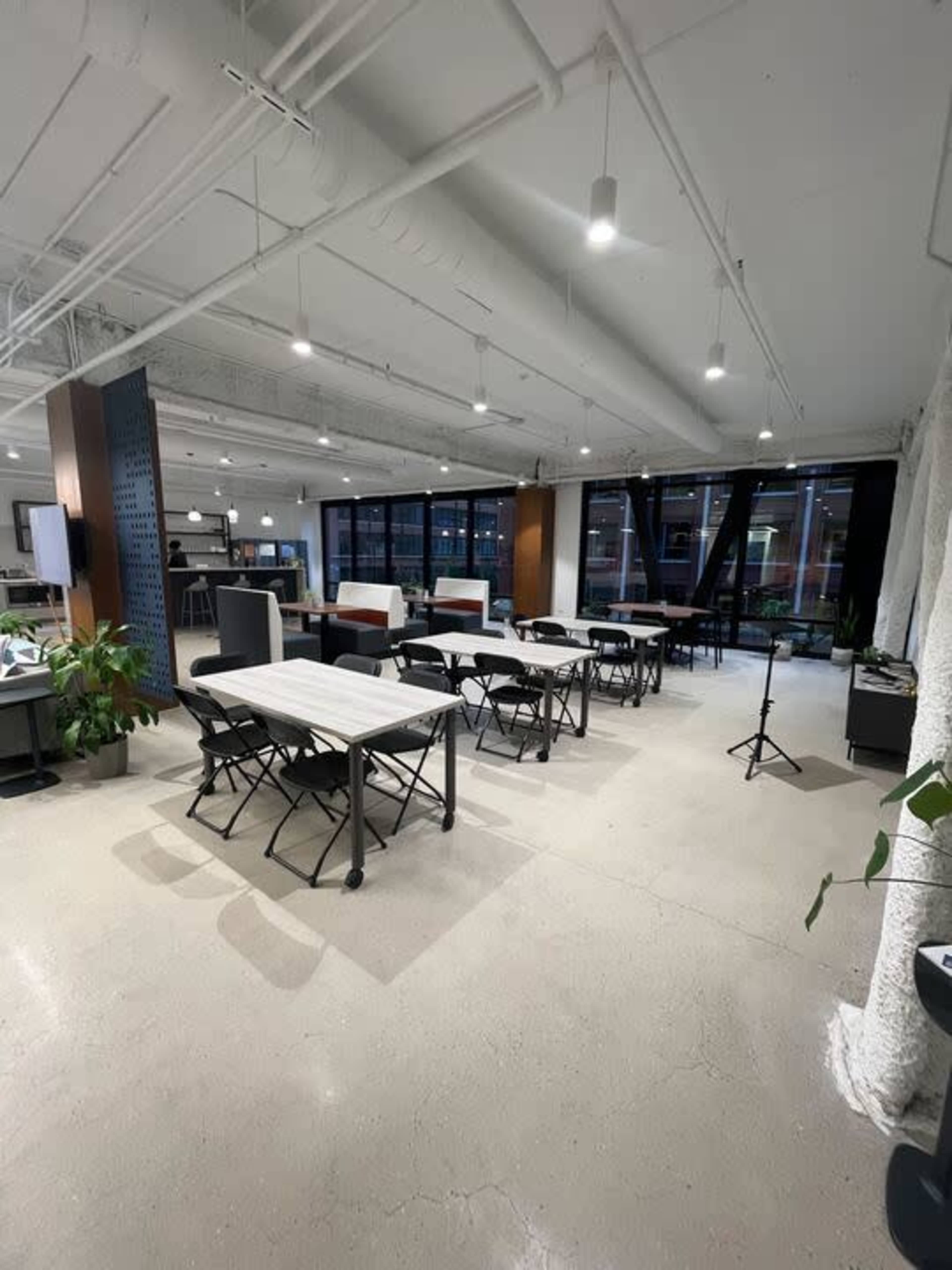 A bright, open office space with multiple folding tables arranged neatly and large windows allowing natural light to enter.