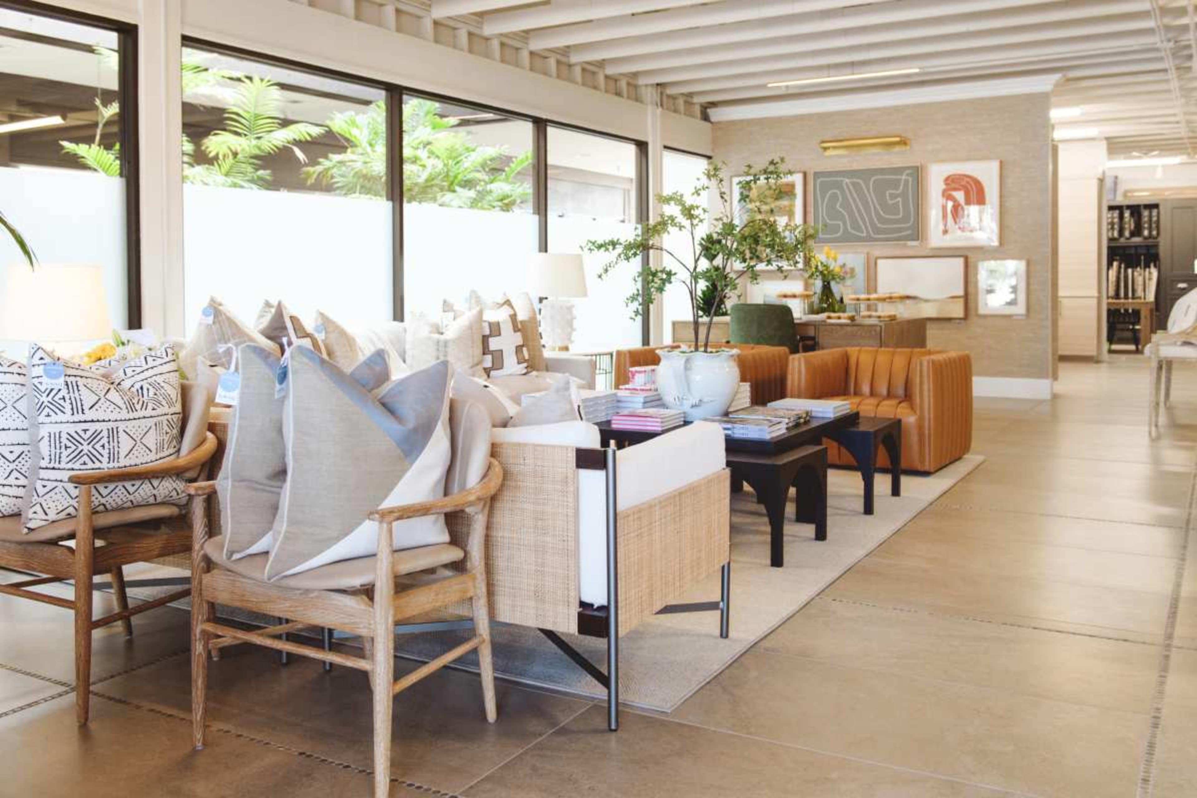 A modern living space featuring various seating options, decorative pillows, and potted plants arranged around a central coffee table.