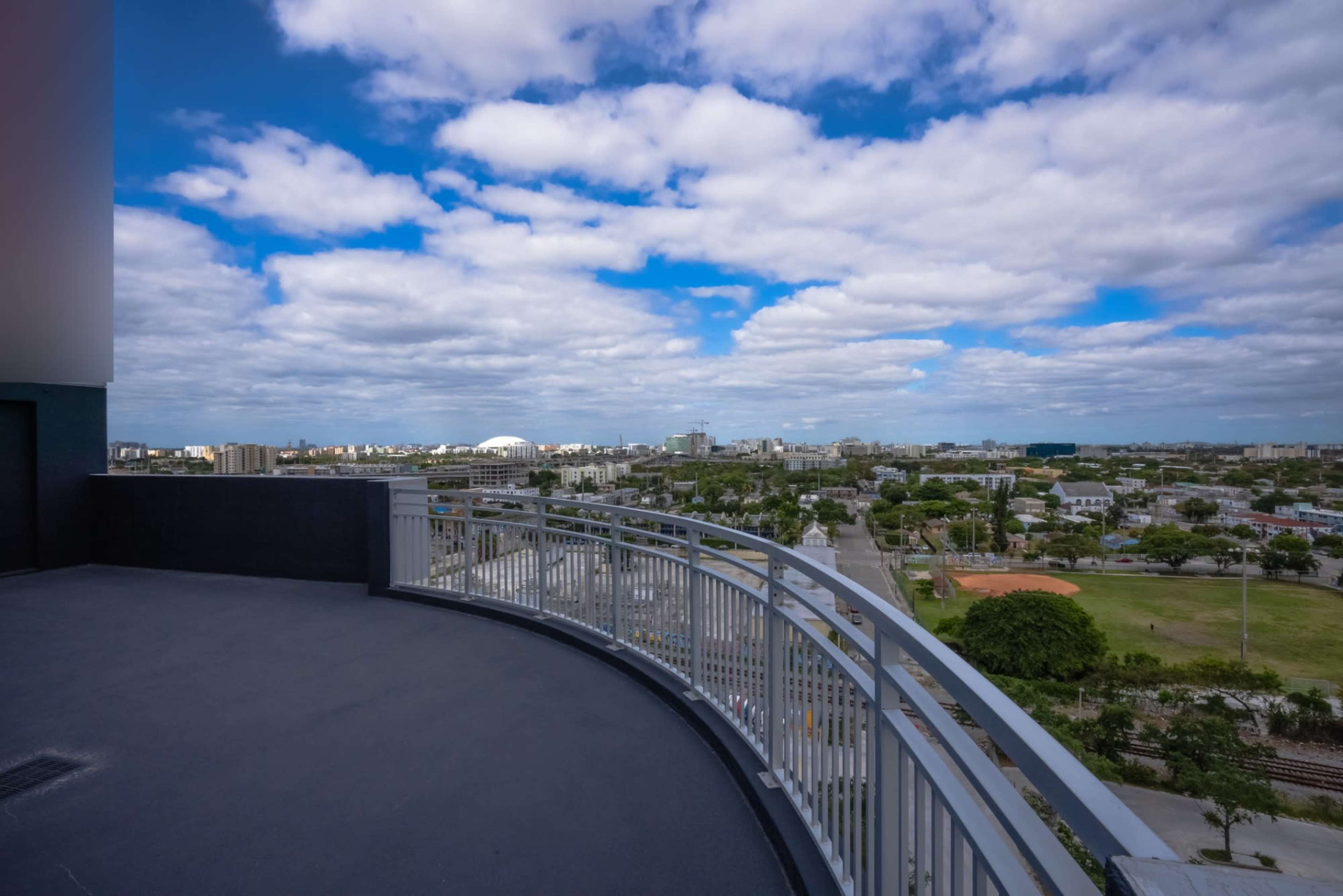 A balcony offers a view of a city skyline under a partly cloudy sky.