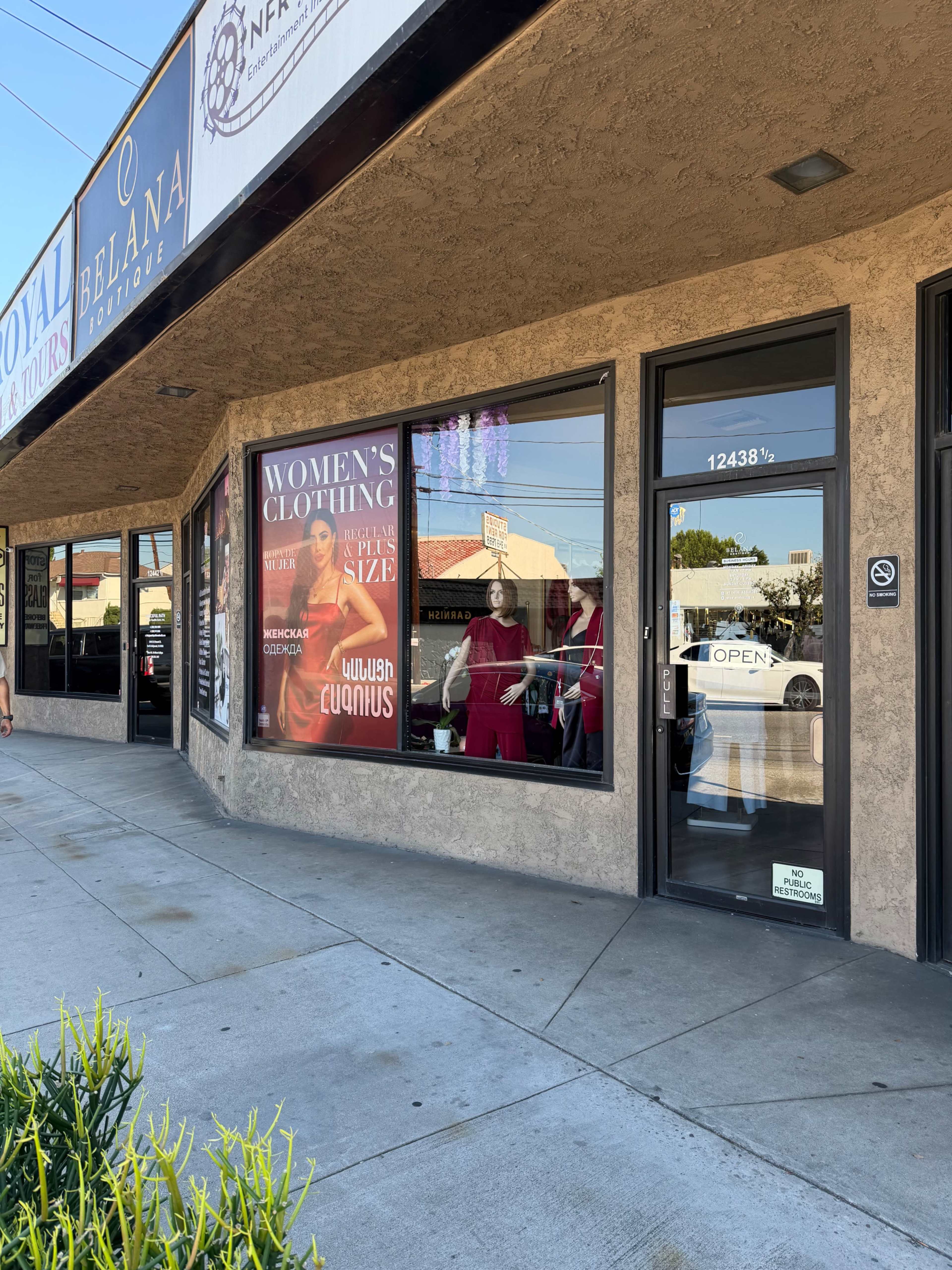 The image shows a storefront featuring a sign for a women's clothing boutique, with a prominent advertisement for clothing in extended sizes displayed in the window.